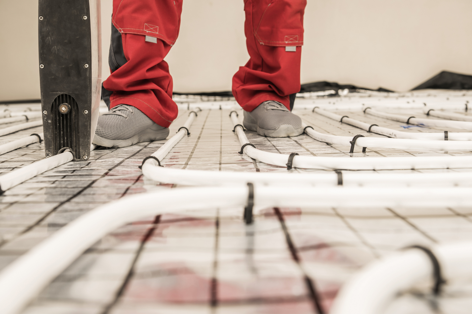 image of in floor heating recently installed with two feet standing in between the piping.