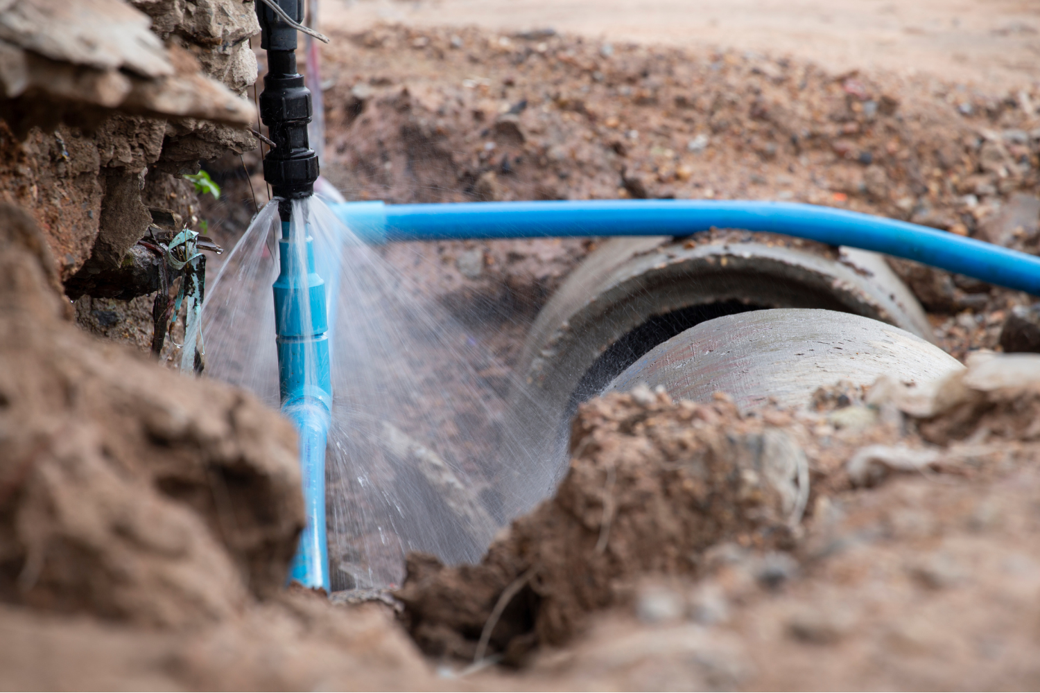 image of a water line in the ground broken and spraying water.