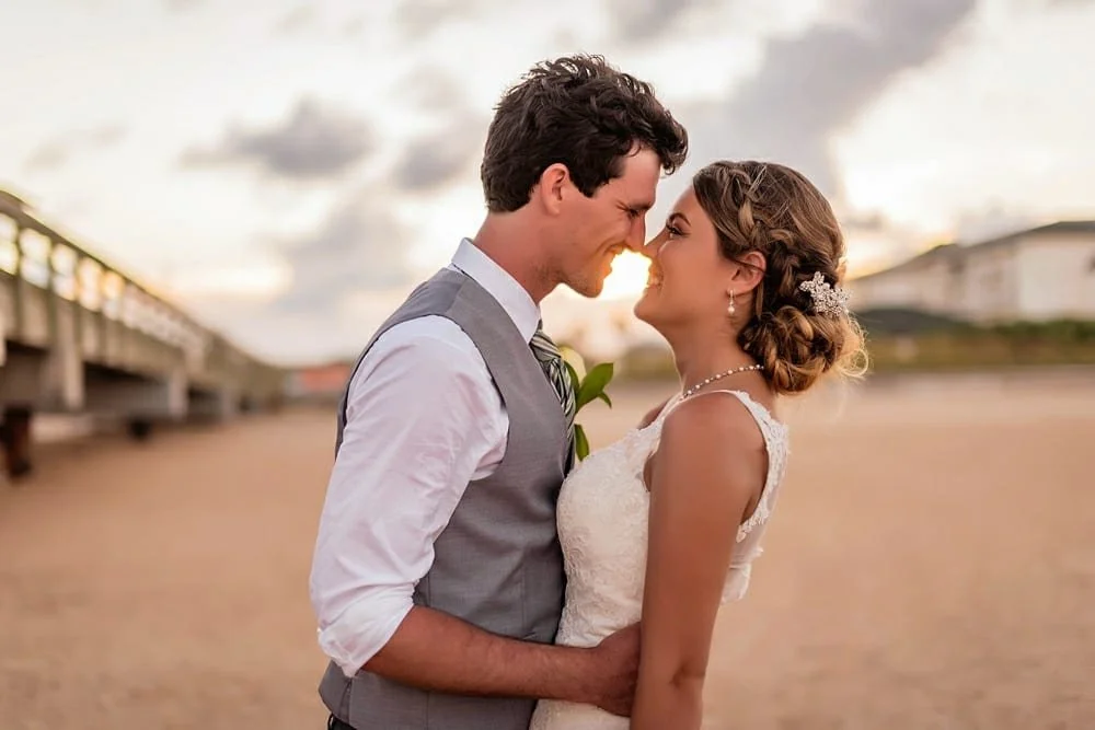 Bride and groom walking down the aisle at a beach wedding, holding hands and smiling, with guests watching and clapping at Vacía Talega.