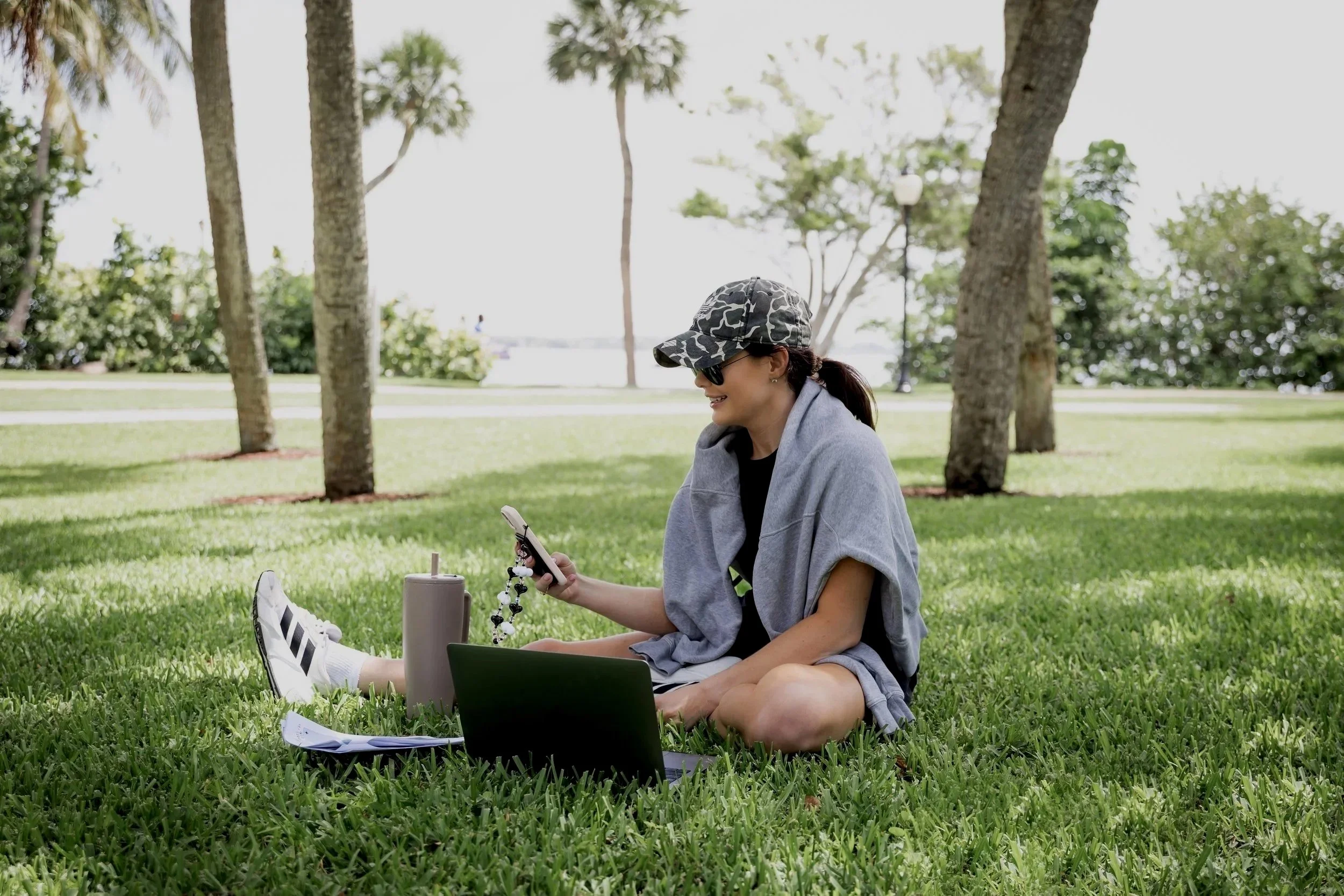 Beauty business admin support professional working remotely on laptop and phone, managing client communication and backend systems for service-based entrepreneurs.