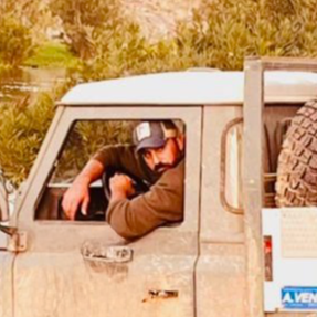 Uomo con cappellino guarda fuori dal finestrino di un veicolo fuoristrada in un'area naturale