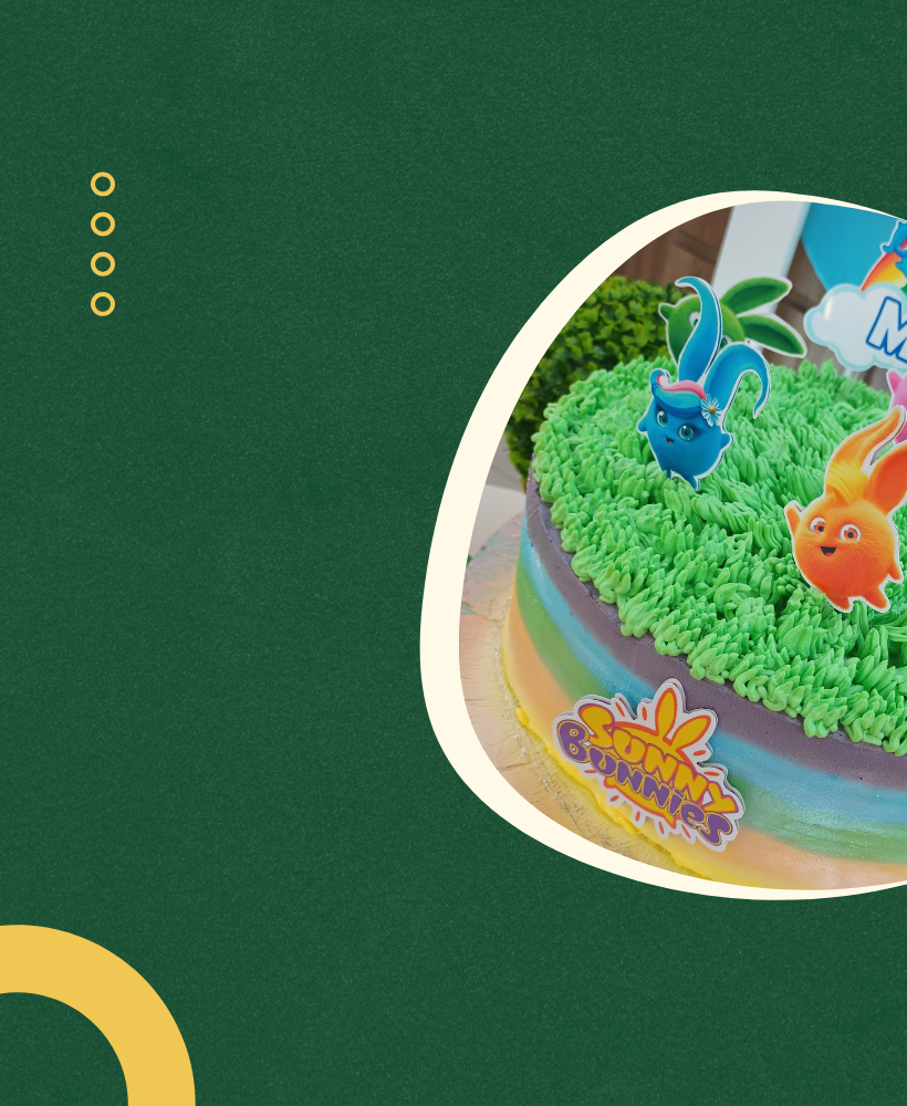 Bolo decorado com tema de coelhinhos coloridos e grama artificial, com uma etiqueta de festa 'Bunny Bums'.