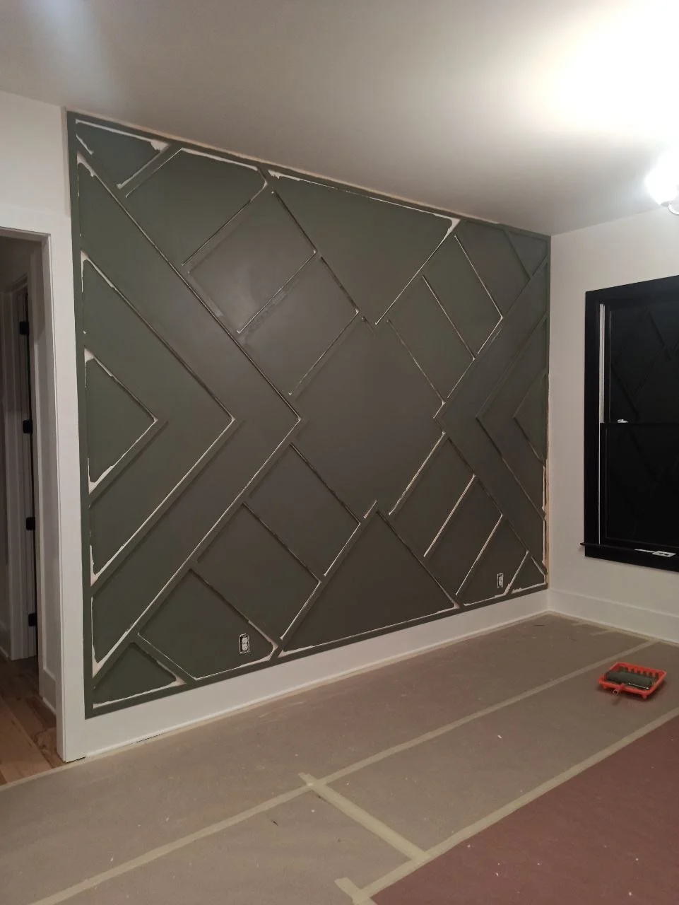 Painted accent wall in deep green color with all trim work finished, prior to gold accent detailing.