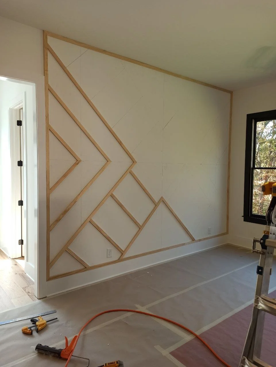 First stage of trim installation showing half-completed geometric pattern on feature wall in Atlanta.