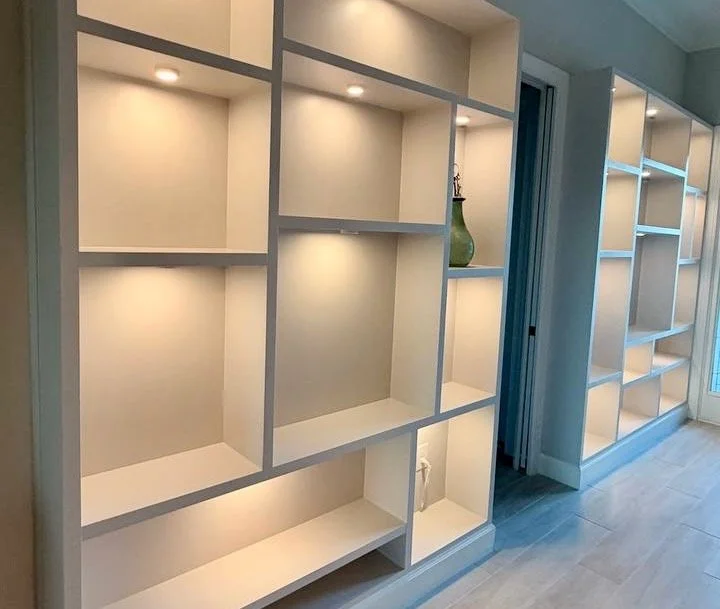 Two coordinated built-in display units with warm niche lighting framing an interior doorway.