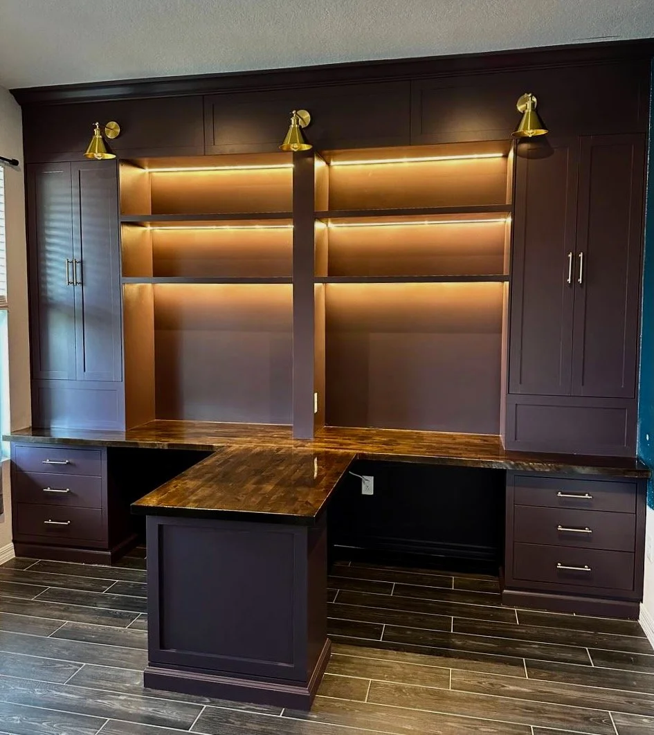 Completed Orlando home office built-ins with two work areas, a wood peninsula, illuminated shelves, and tall cabinets.
