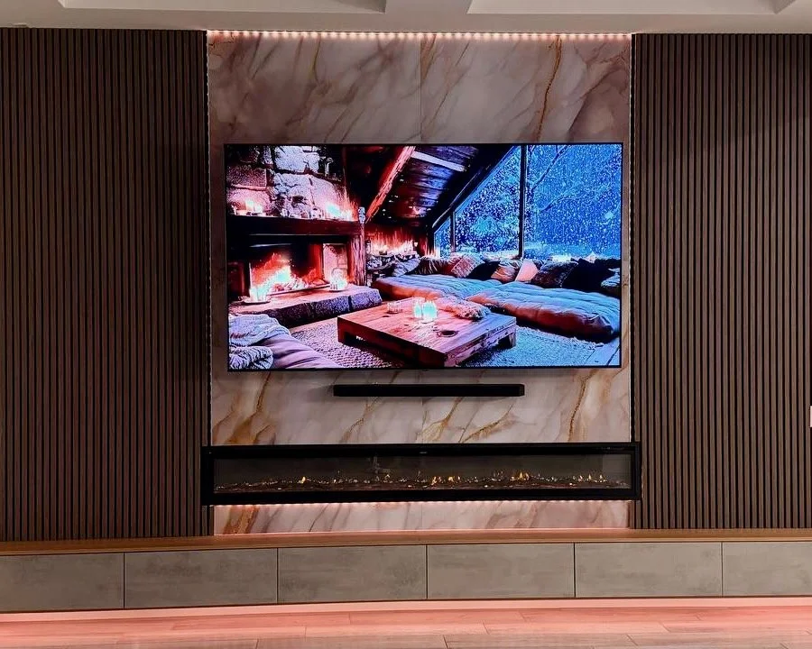 Close-up of modern fireplace media wall with marble-look panels and wood slat accents in Englewood FL