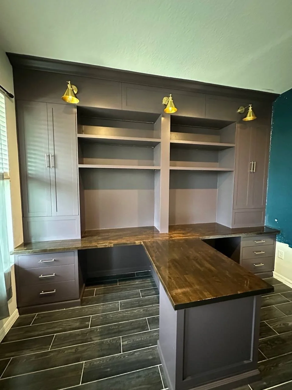 T-shaped wood desk with a central peninsula, drawer units, and full-wall painted cabinetry in an Orlando home office.