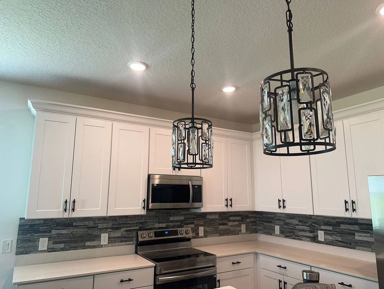 Crown molding and stone backsplash details above white cabinets – Orlando kitchen project.