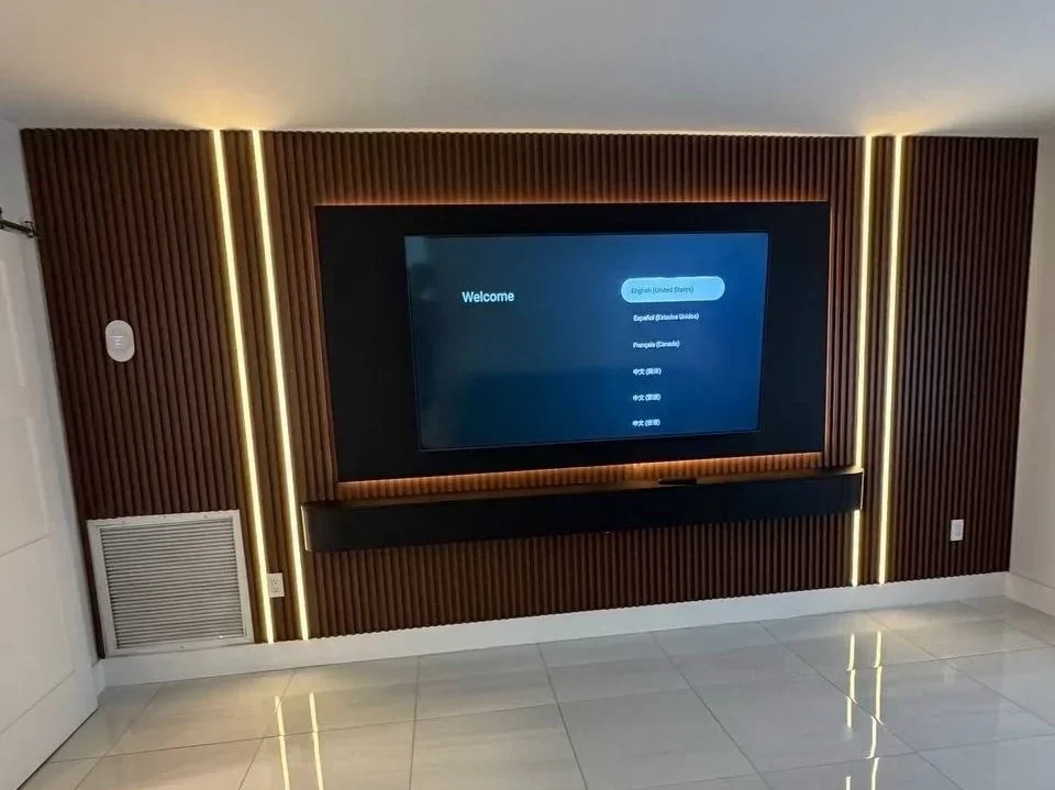 Miami-area TV wall with wood-look slats, vertical LED lighting, a backlit dark TV panel, and a floating media cabinet.