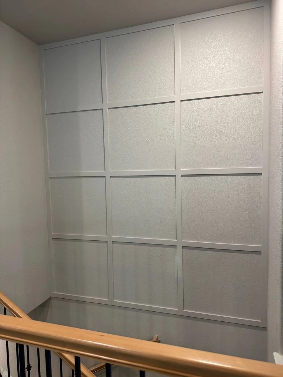 Decorative grid wall design with symmetrical trim in a two-story staircase.