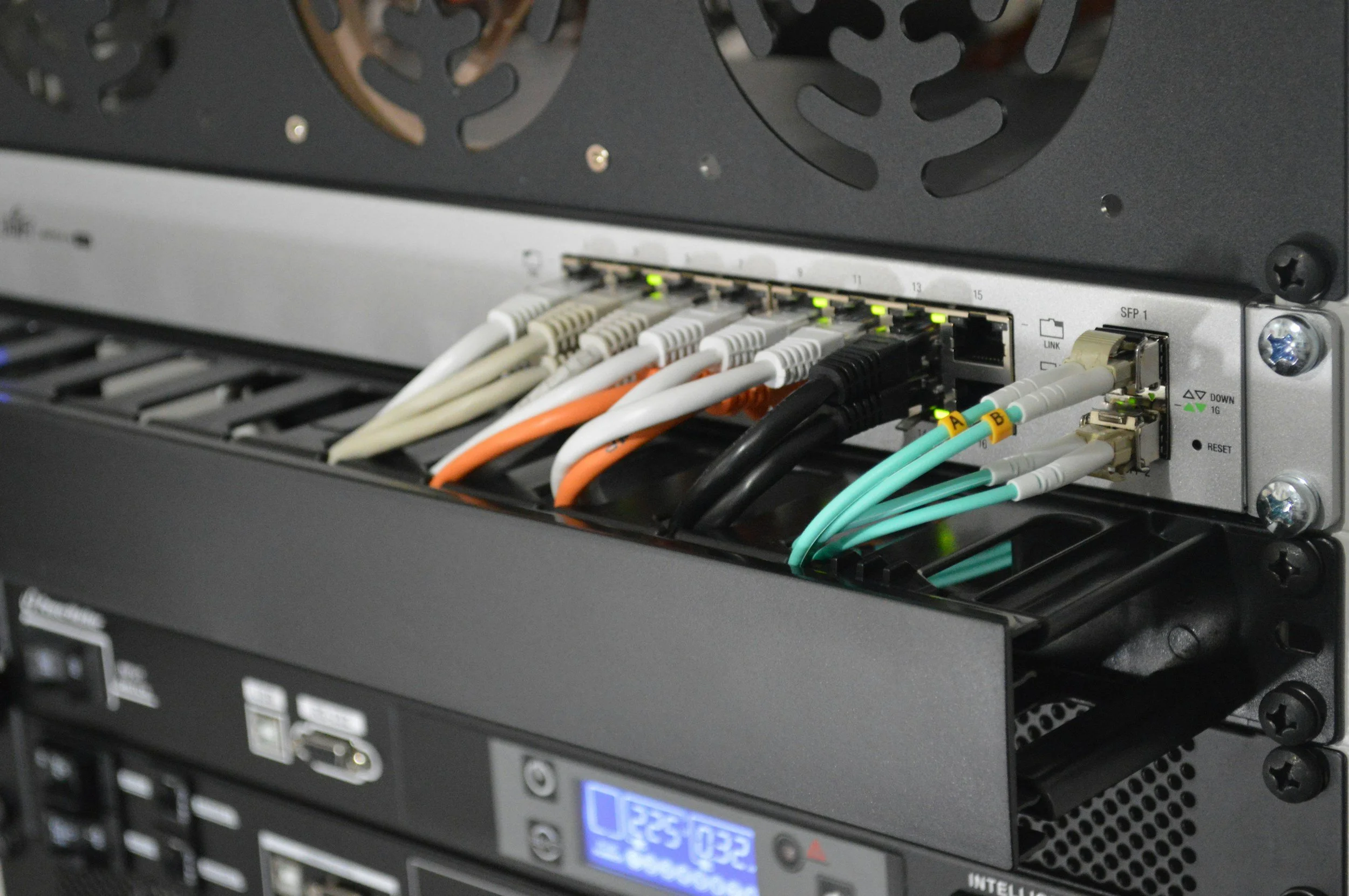 Close-up of a network server with multiple color-coded Ethernet cables connected to it.