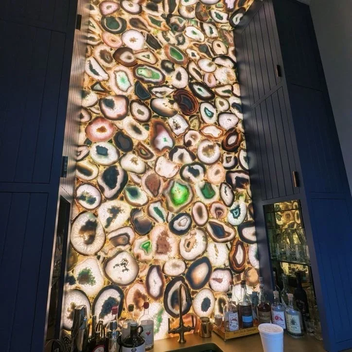 Large illuminated wall art featuring colorful geodes or agate slices in a vertical display in a bar or restaurant setting.