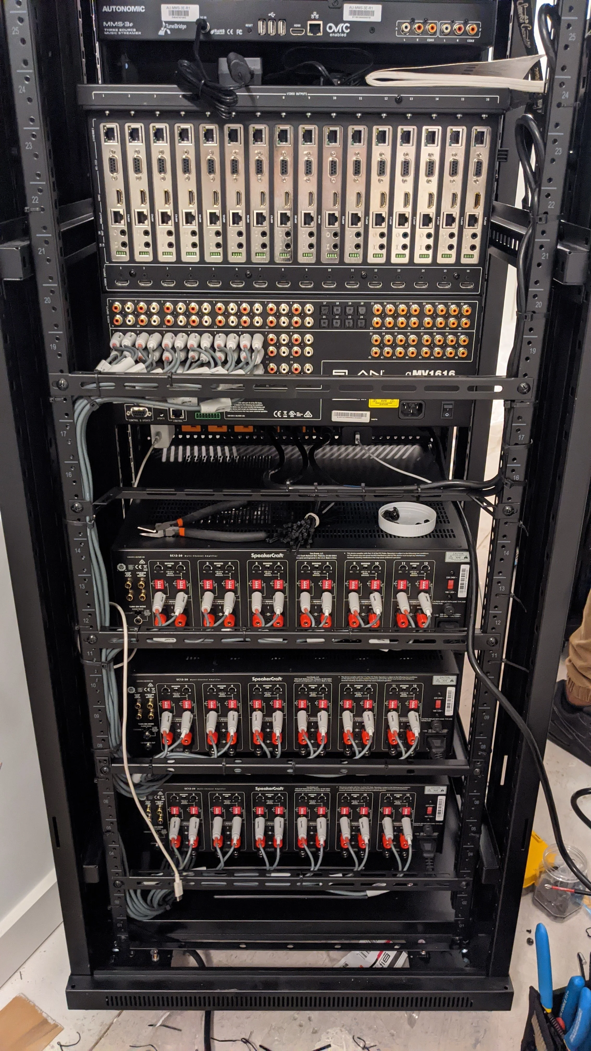 A server rack with various electronic equipment, including audio signal processors, with multiple cables connected to the devices.