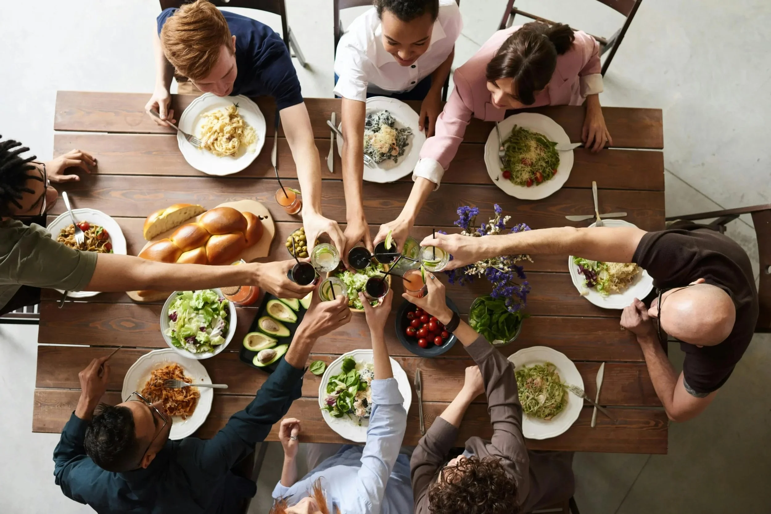 Group of Jewish people around a table enjoying a meal and toasting with drinks.