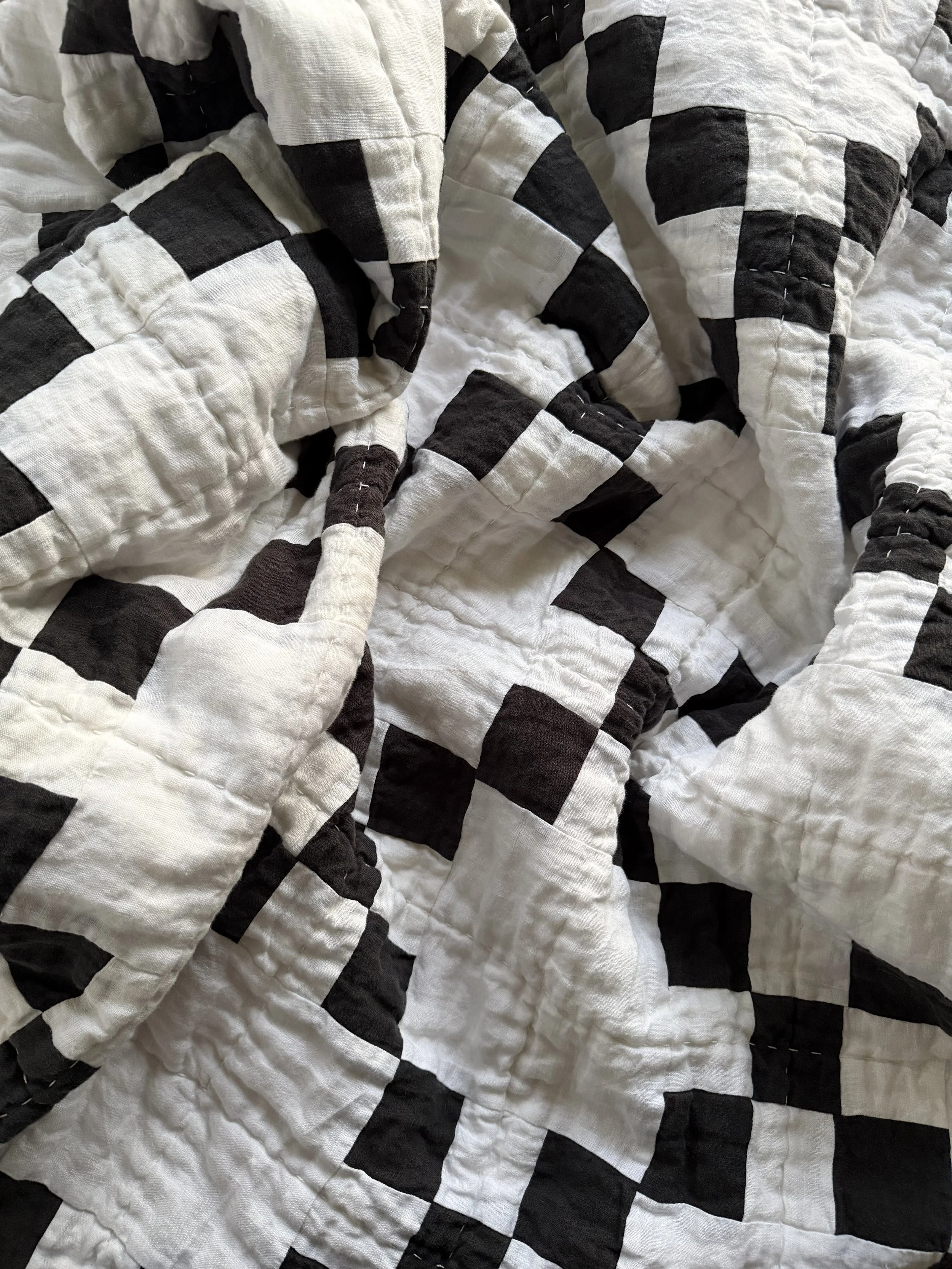 Close-up of a bed with a black and white checkered quilt.