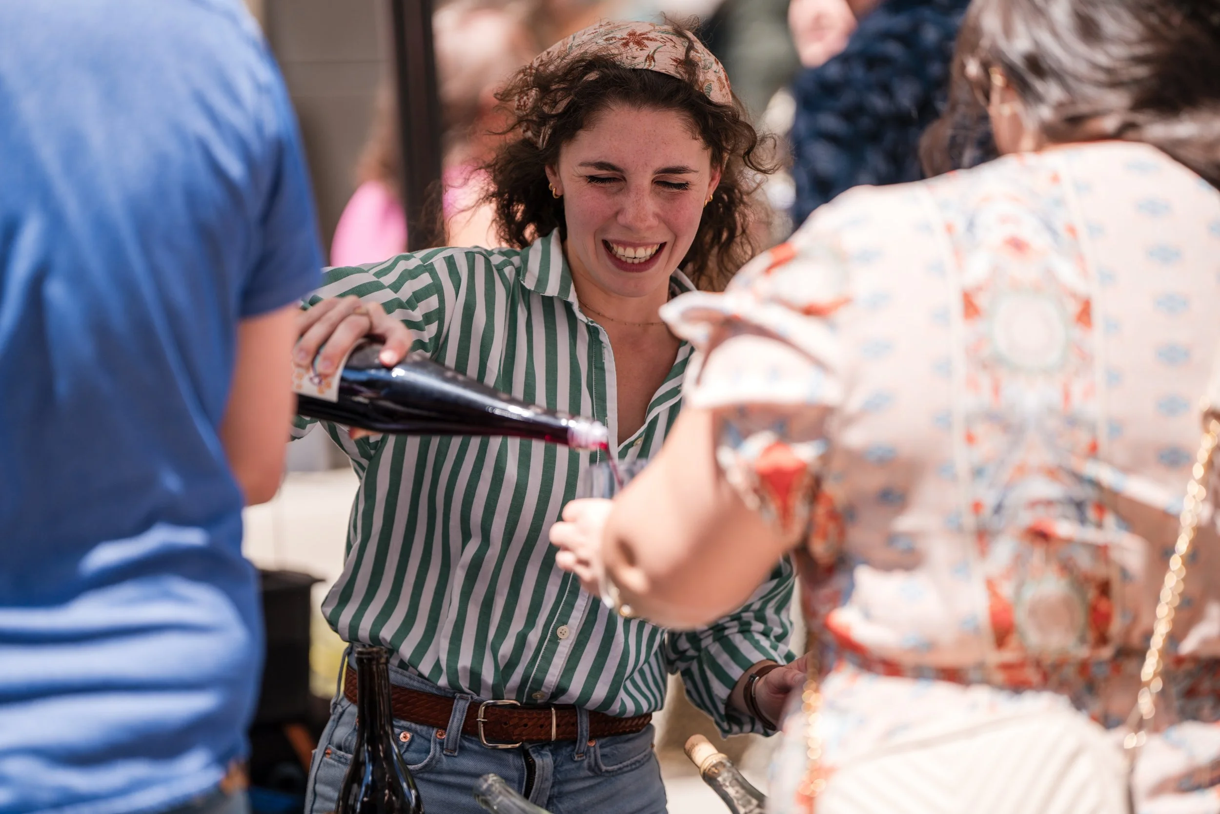 A bartender pouring red wine into a glass for a festival attendee.