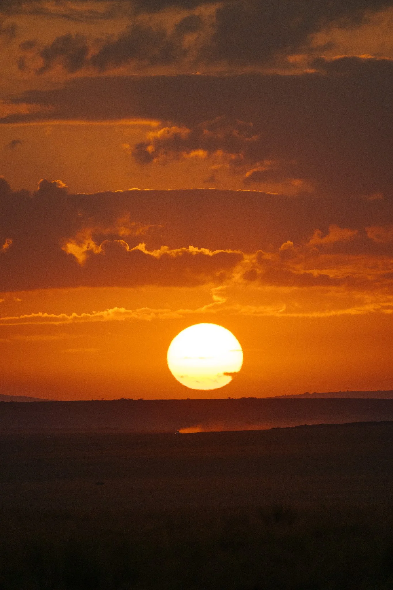Sun setting over a landscape with clouds in the sky.