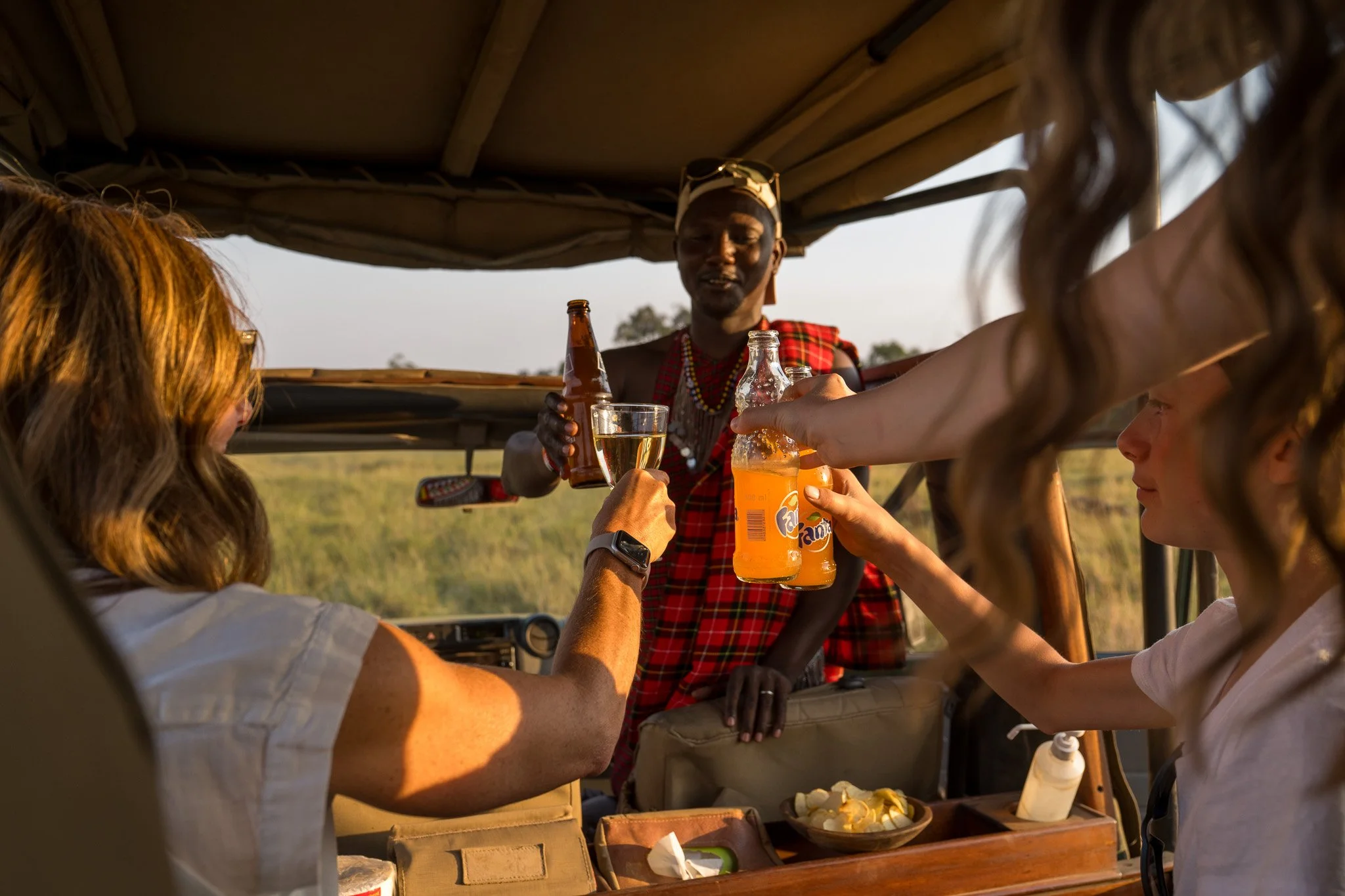 A safari vehicle with a local guide serving drinks to tourists during a safari ride in Africa.