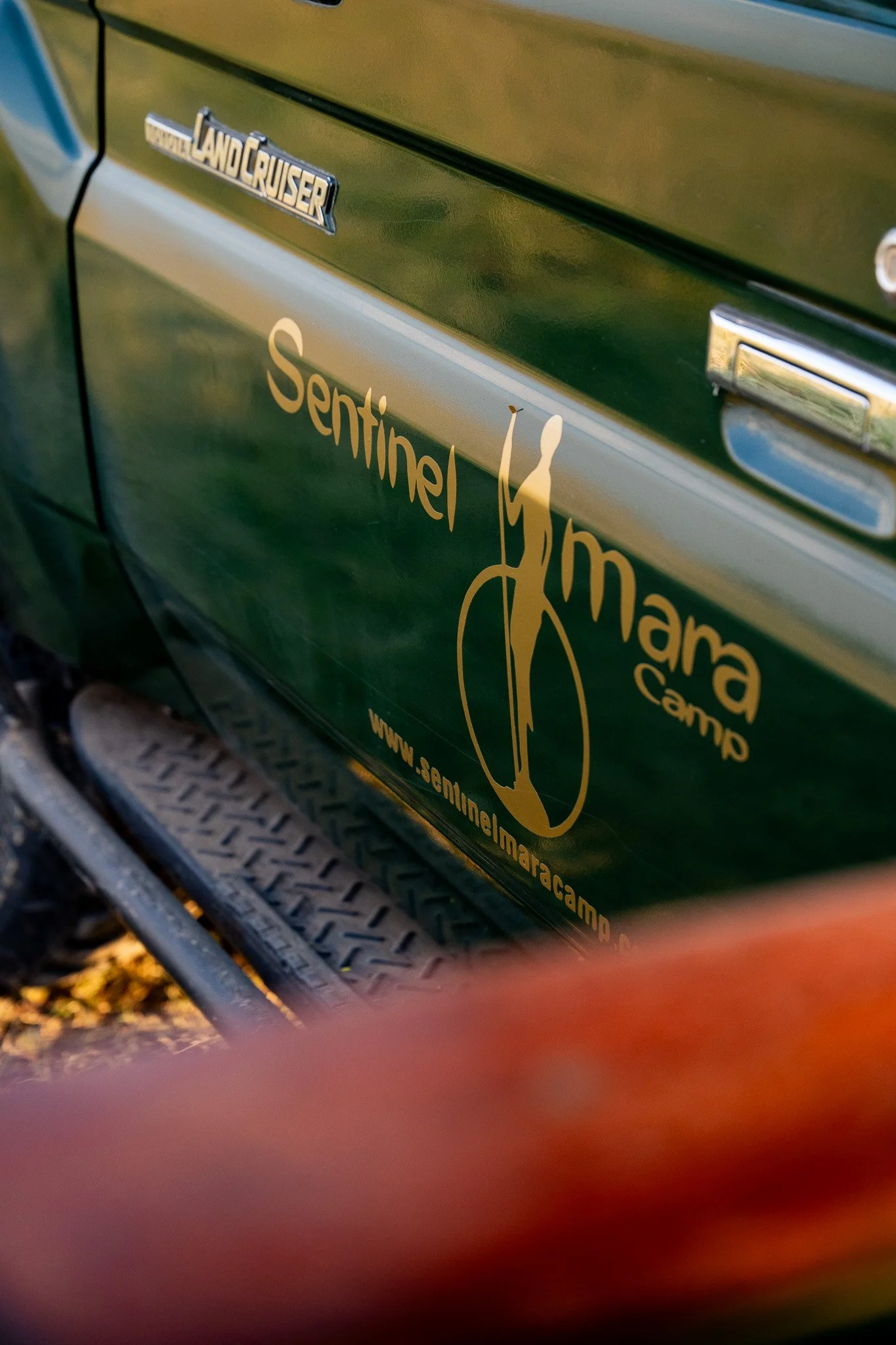 Close-up of a green vehicle door with Land Cruiser and Sentinel Maramar Camp logos.