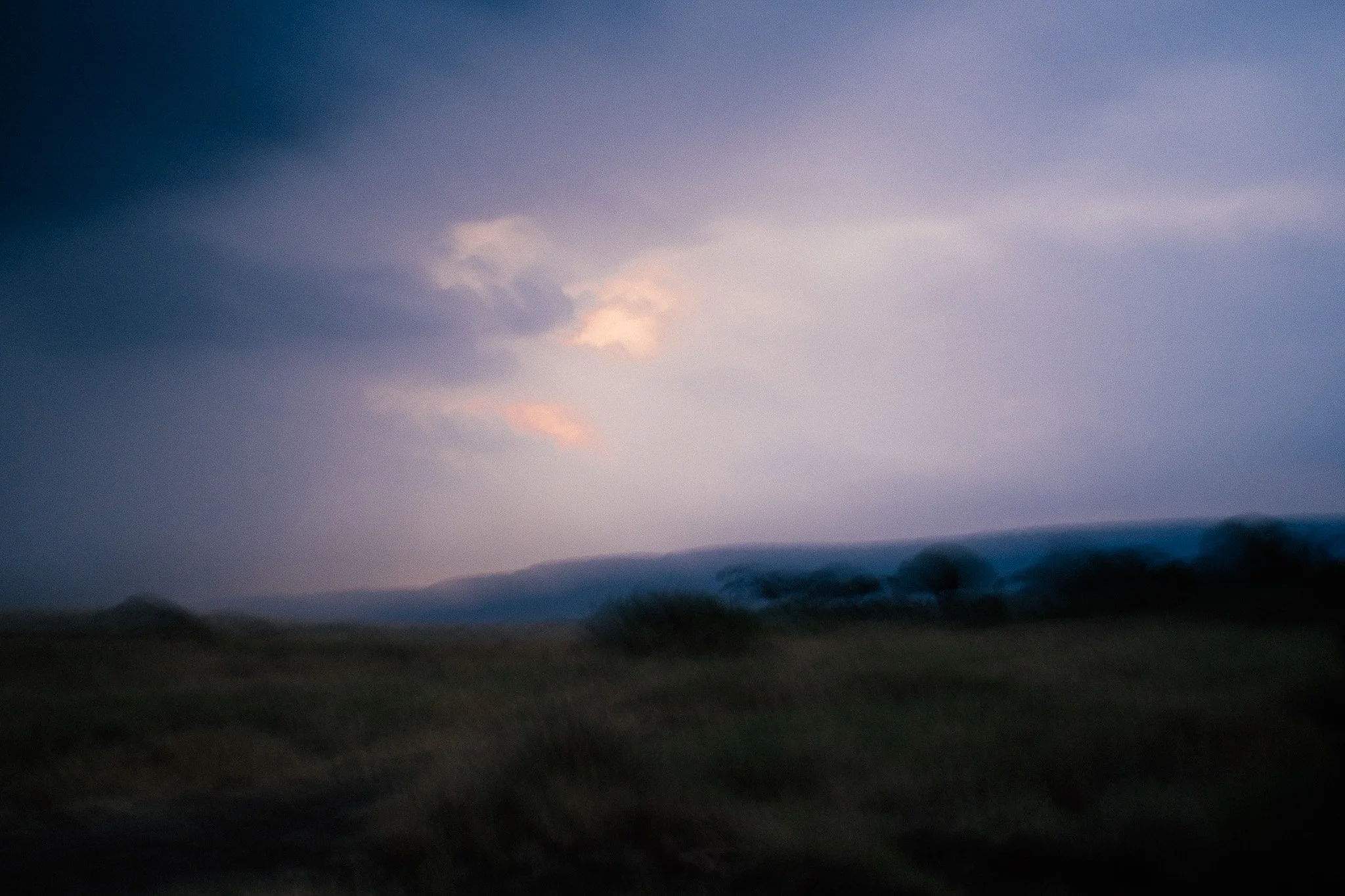 A landscape view of distant mountains with a cloudy sky during dusk or dawn.