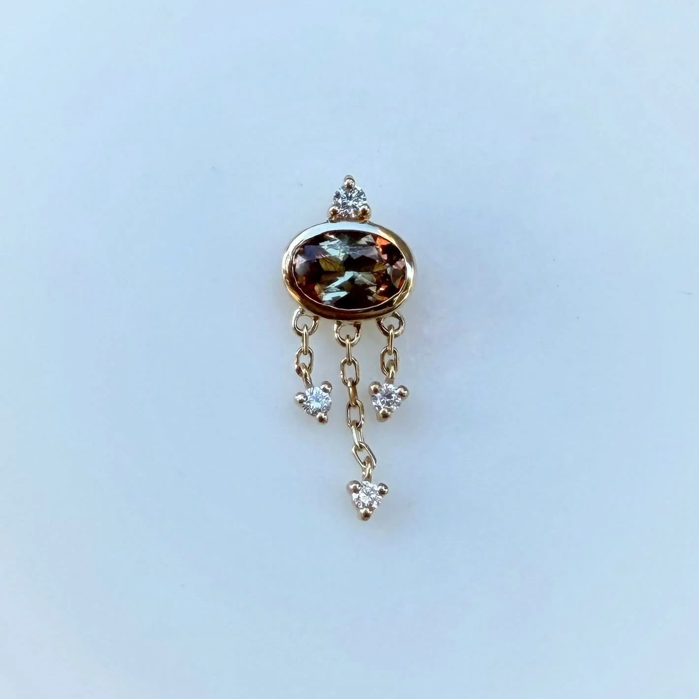 We are in awe over this new piece from @modernmoodbodyjewelry ! It is incredibly unique with its distinct orange and green tones, and would be a beautiful addition to any collection. The larger stone is a gem called Andalusite, and the accents are al