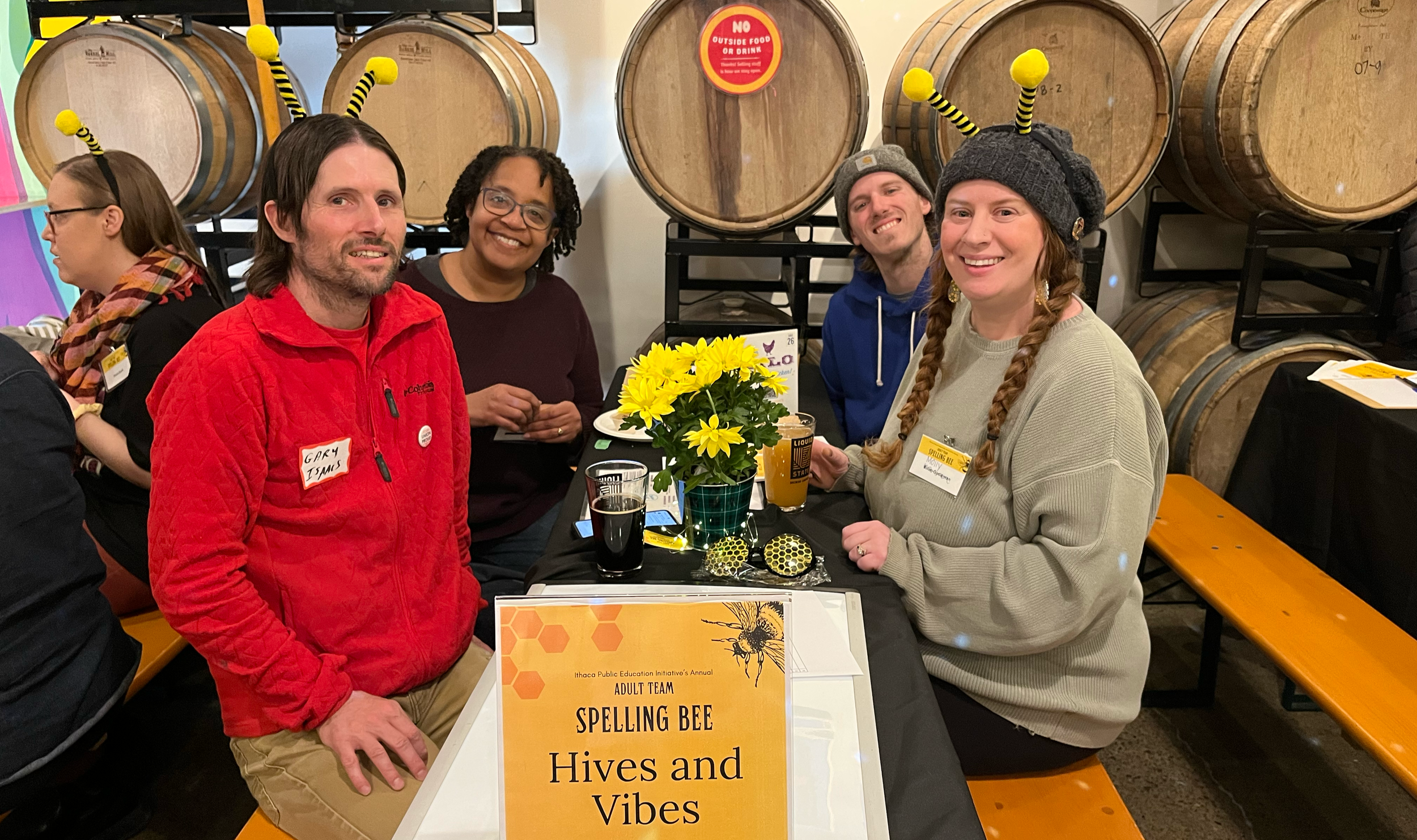 Four people wearing bee antennae smile at the camera as they participate in the 2024 Adult Team Spelling Bee 