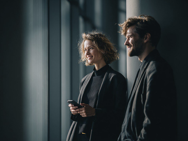 Woman standing next to man holding her mobile