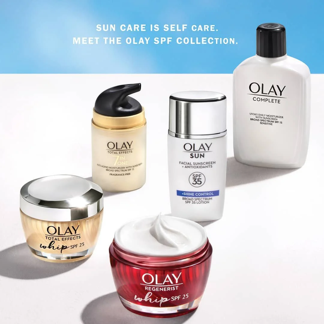 Collection of Olay skincare products including moisturizers and sunscreens against a blue and white background, with text "Sun care is self care. Meet the Olay SPF collection."