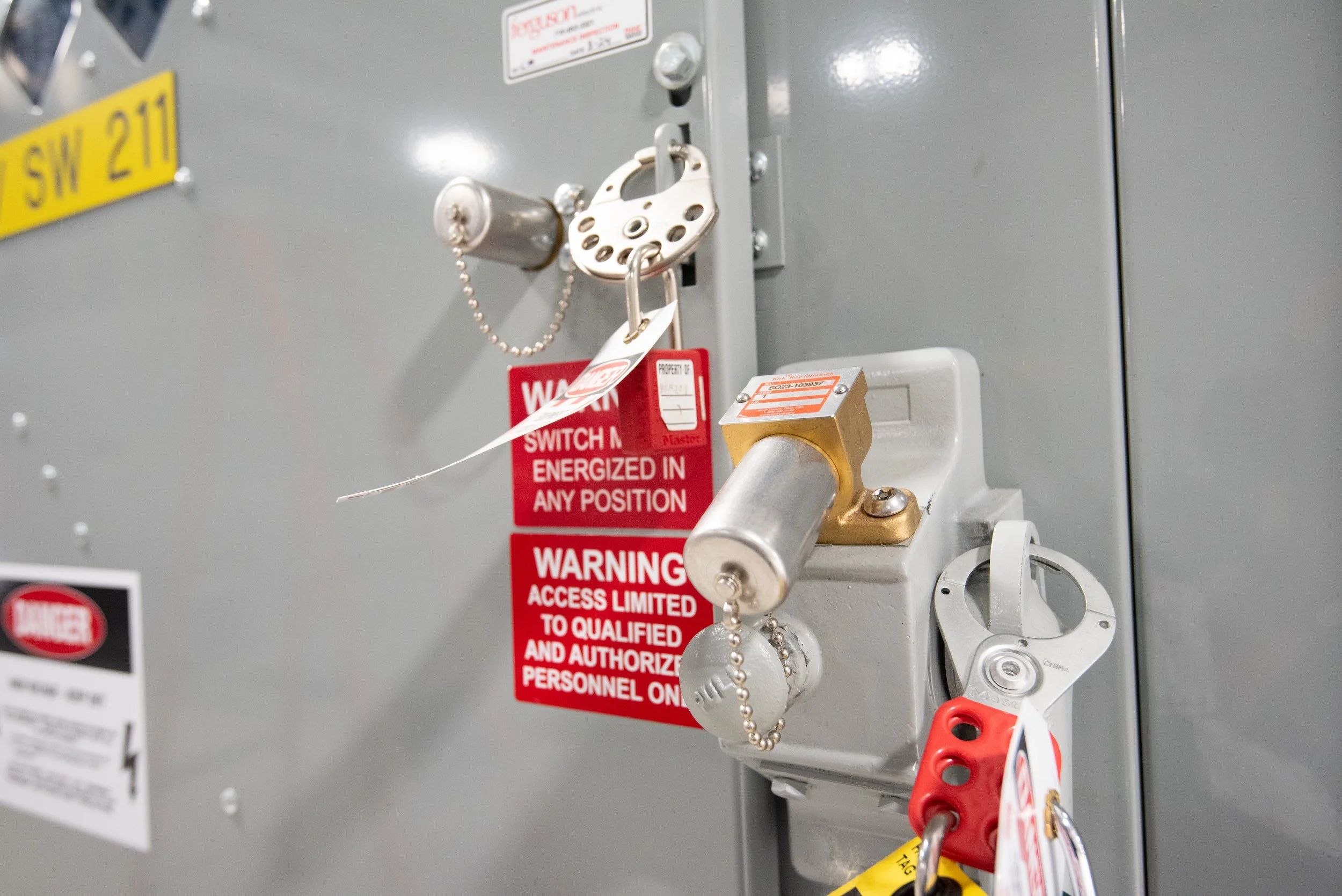 Electrical control panel with lockout device and warning labels, including a lock, key chain, and a warning sign indicating limited access.