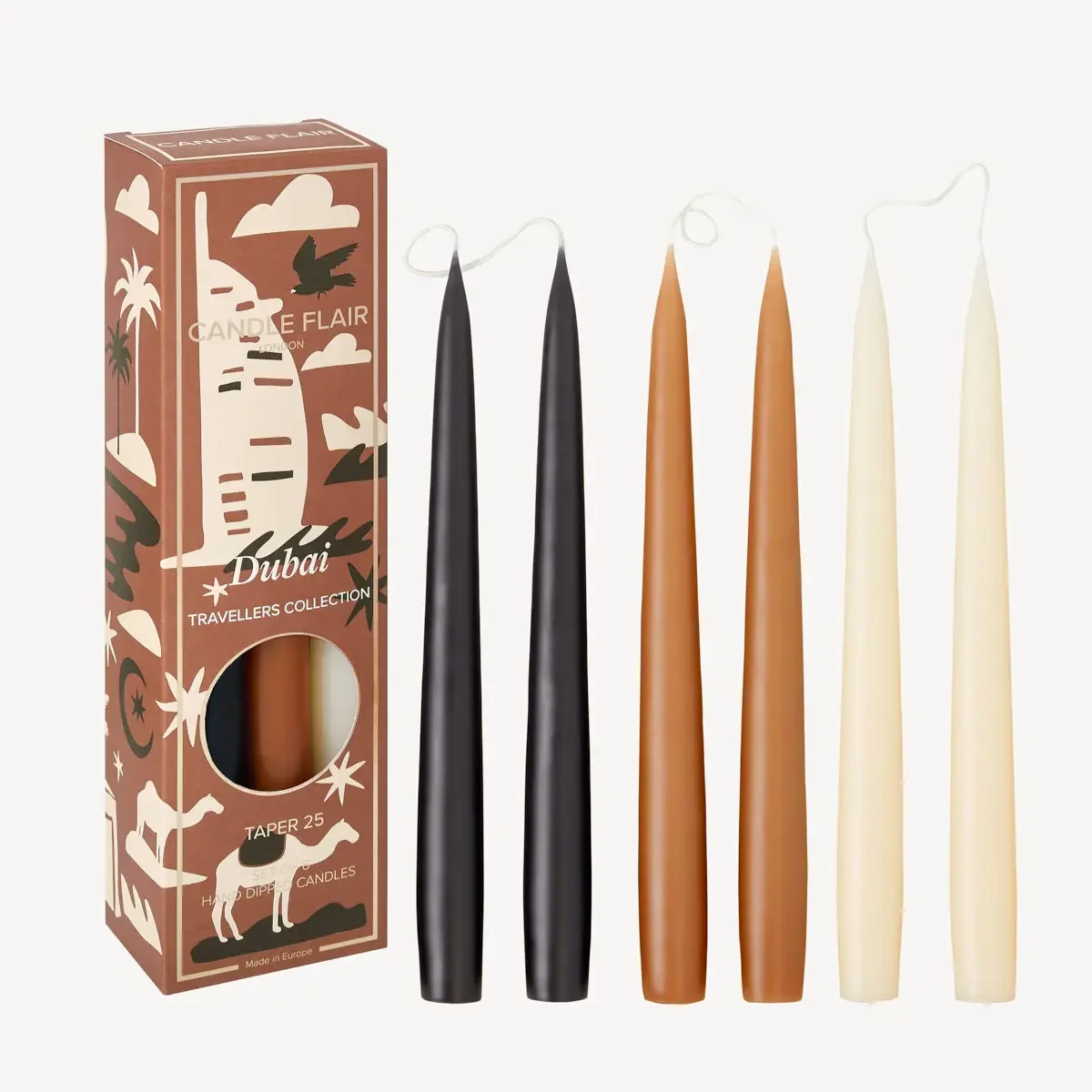 Set of five taper candles in black, brown, and ivory colors beside their packaging box on a white background.