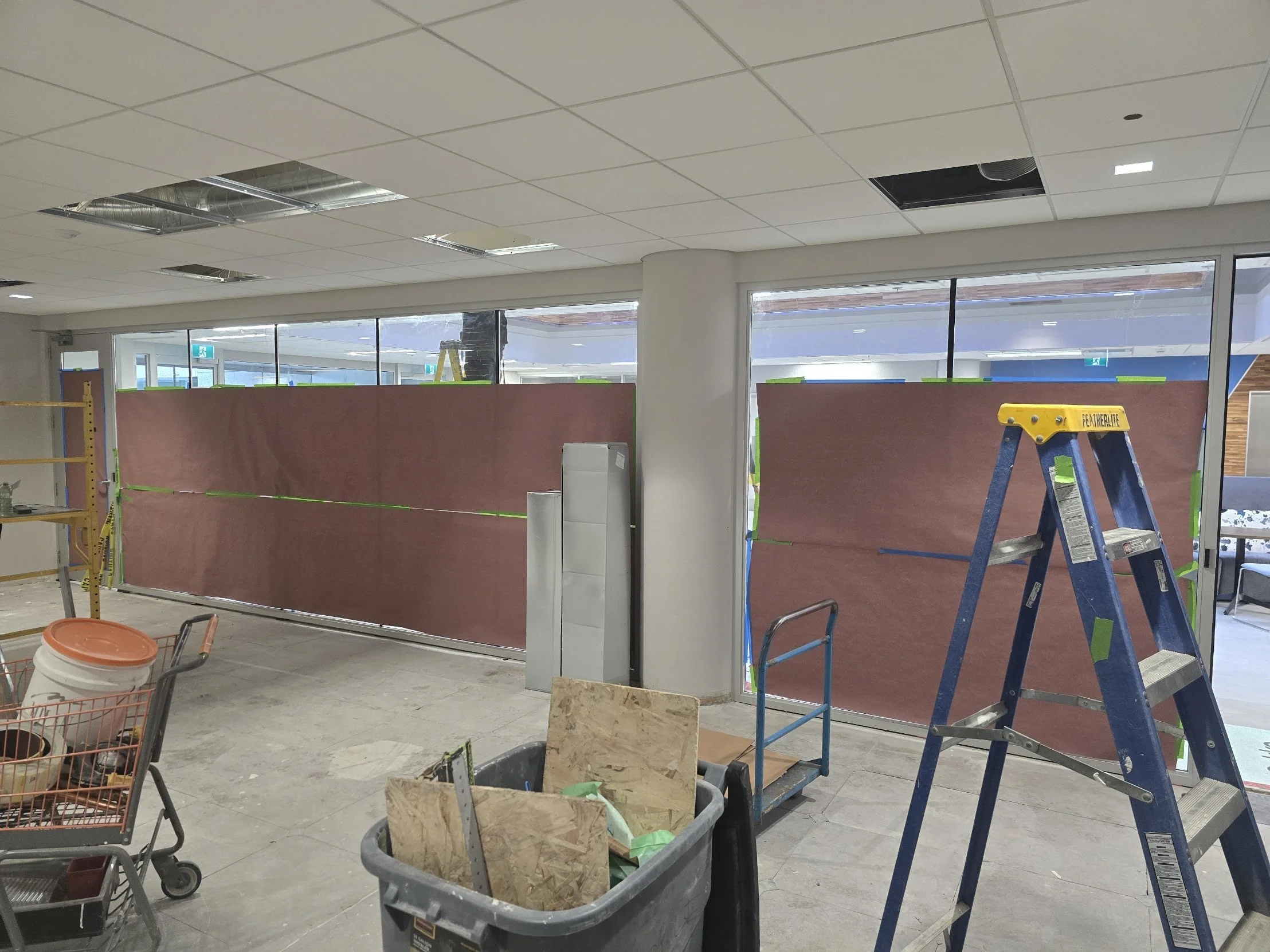 Construction site inside a building with work tools, a ladder, and barriers, indicating renovation or construction work.