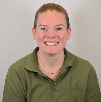 Et smilende portrætfoto af en kvinde med rødt hår i en grøn polo, foran en grå baggrund.