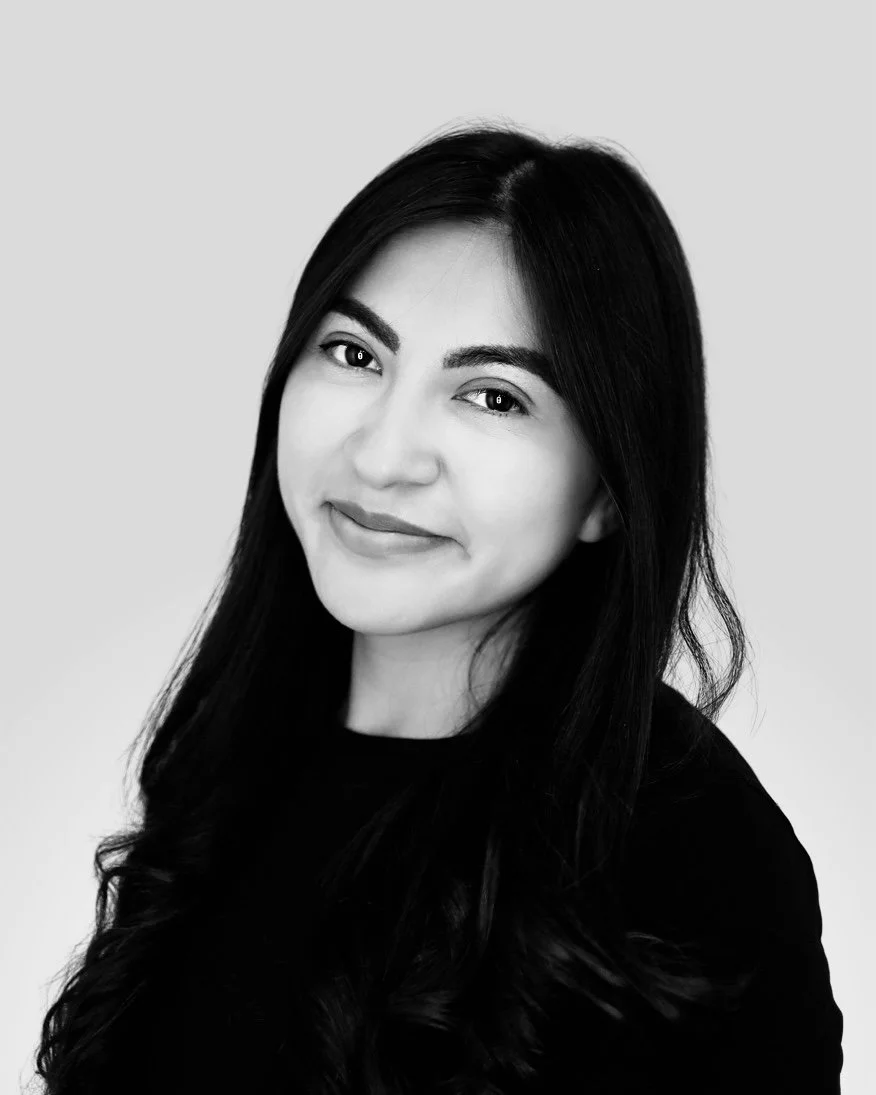 Black and white portrait of a young woman with long dark hair, smiling softly, wearing a dark shirt, against a light background.