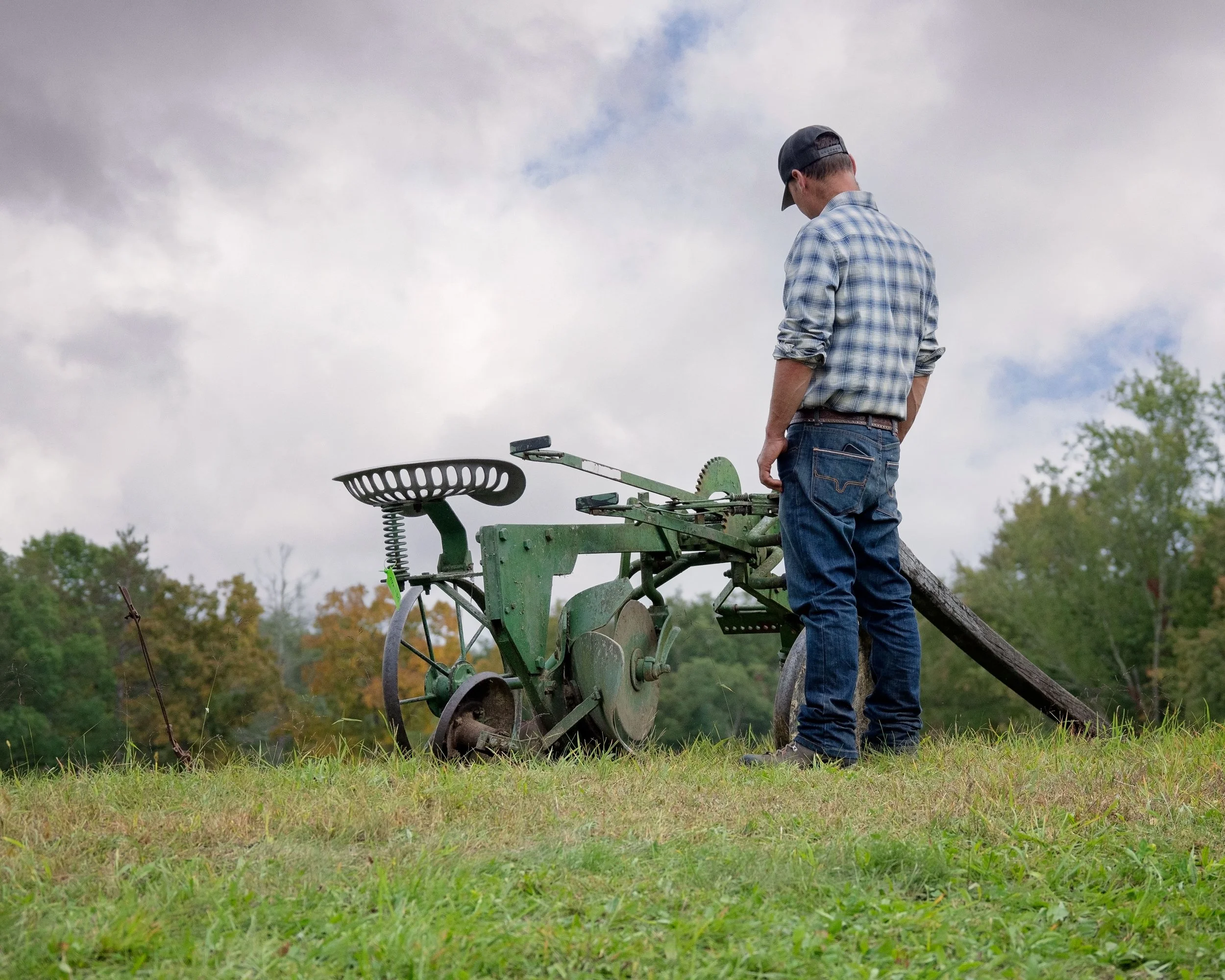Farmer inspects farm equipment at Draft Animal Power Field Days 2024. Carole Wiley photo.