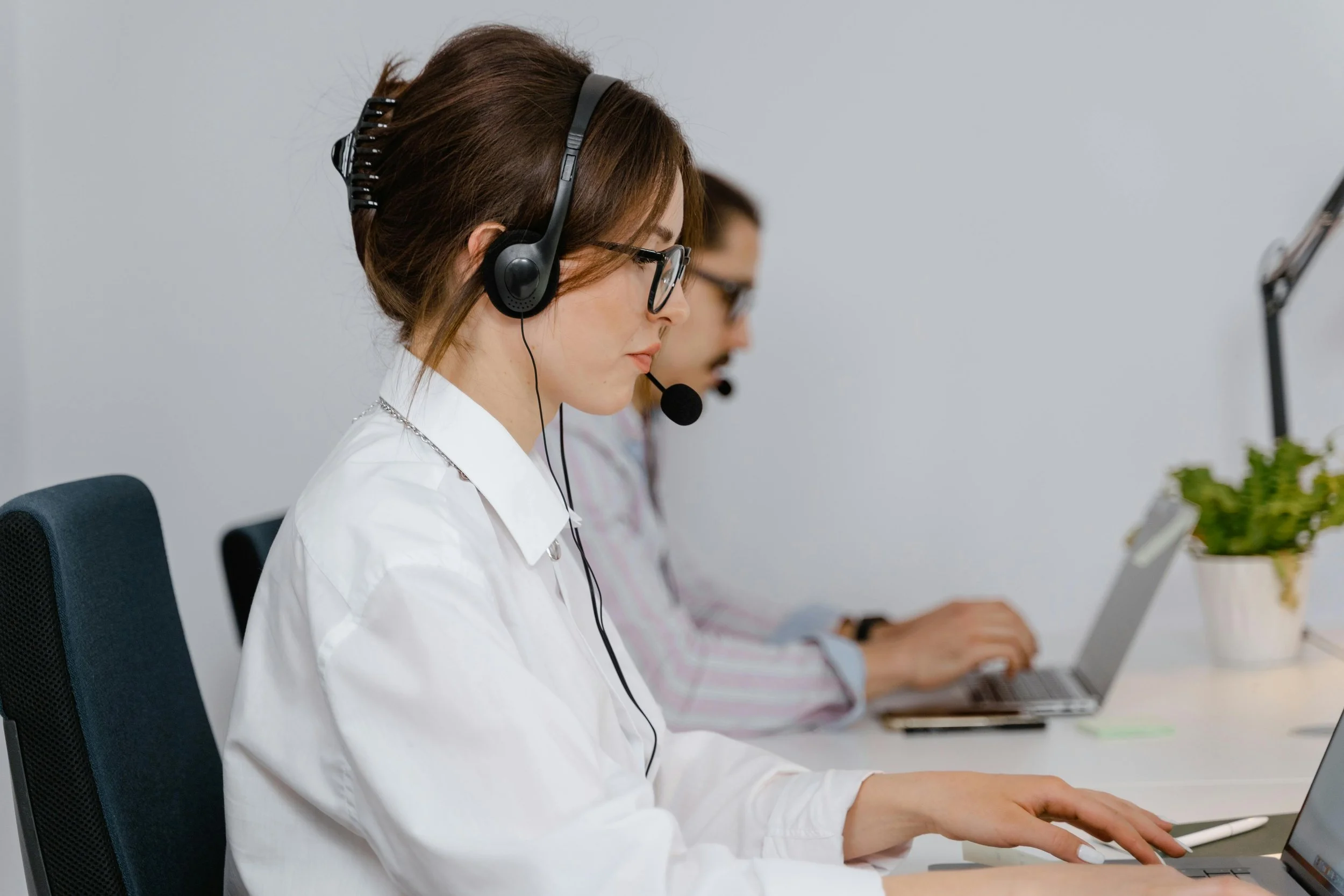 A woman with a headset on working at a computer