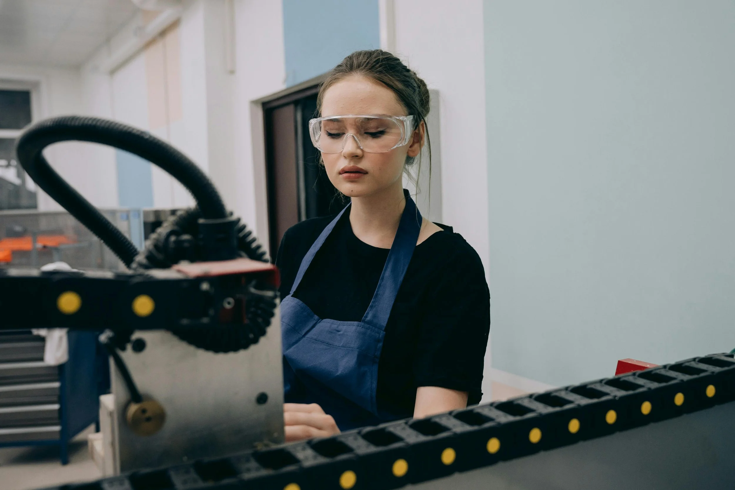 A woman with goggles on working at a conveyor belt