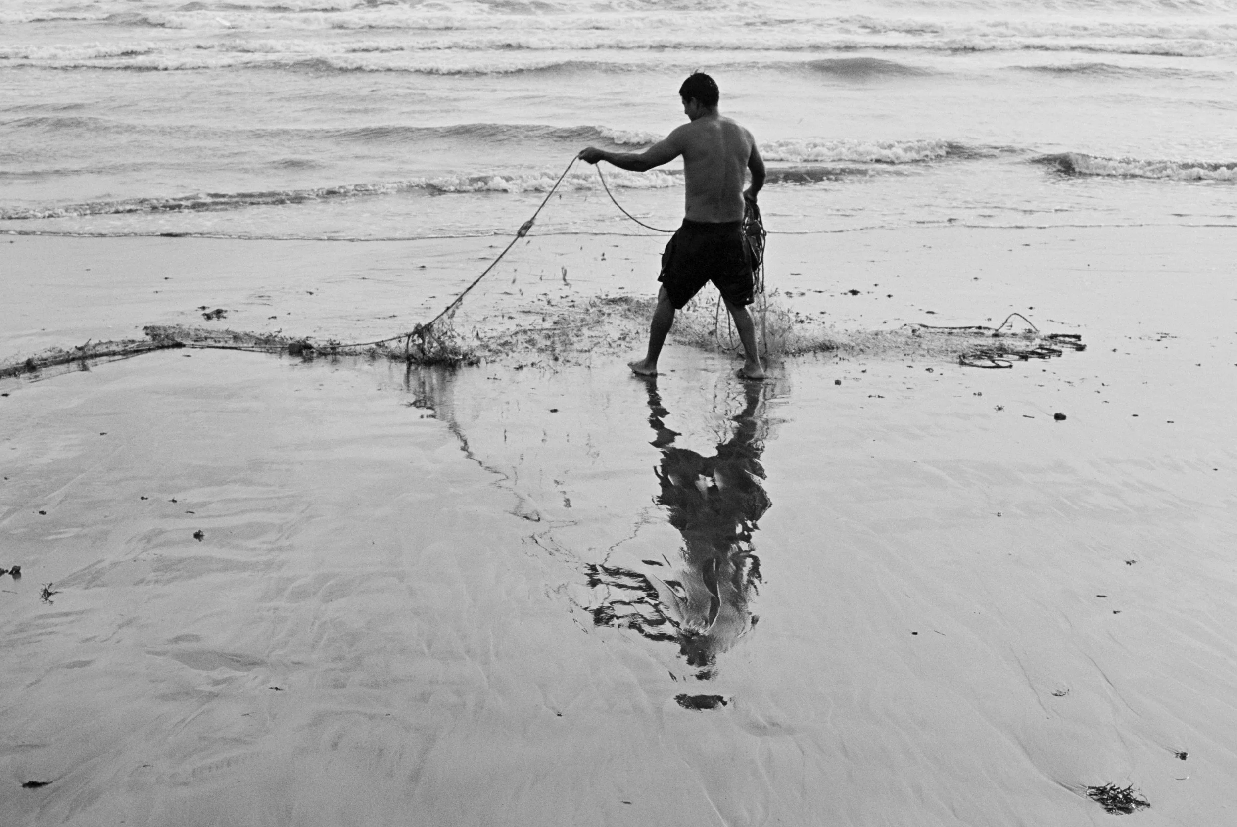 A man standing in shallow ocean water. Perú 2025