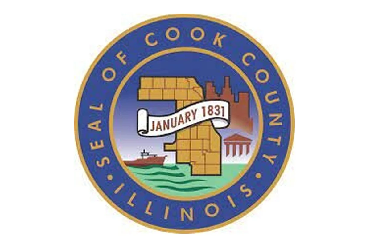 Seal of the Illinois State Library, featuring a yellow Illinois map, a white ribbon with 'January 1831', a factory, a lighthouse, a small building, and water, surrounded by a blue border with gold text that reads 'Seal of the Illinois State Library'.
