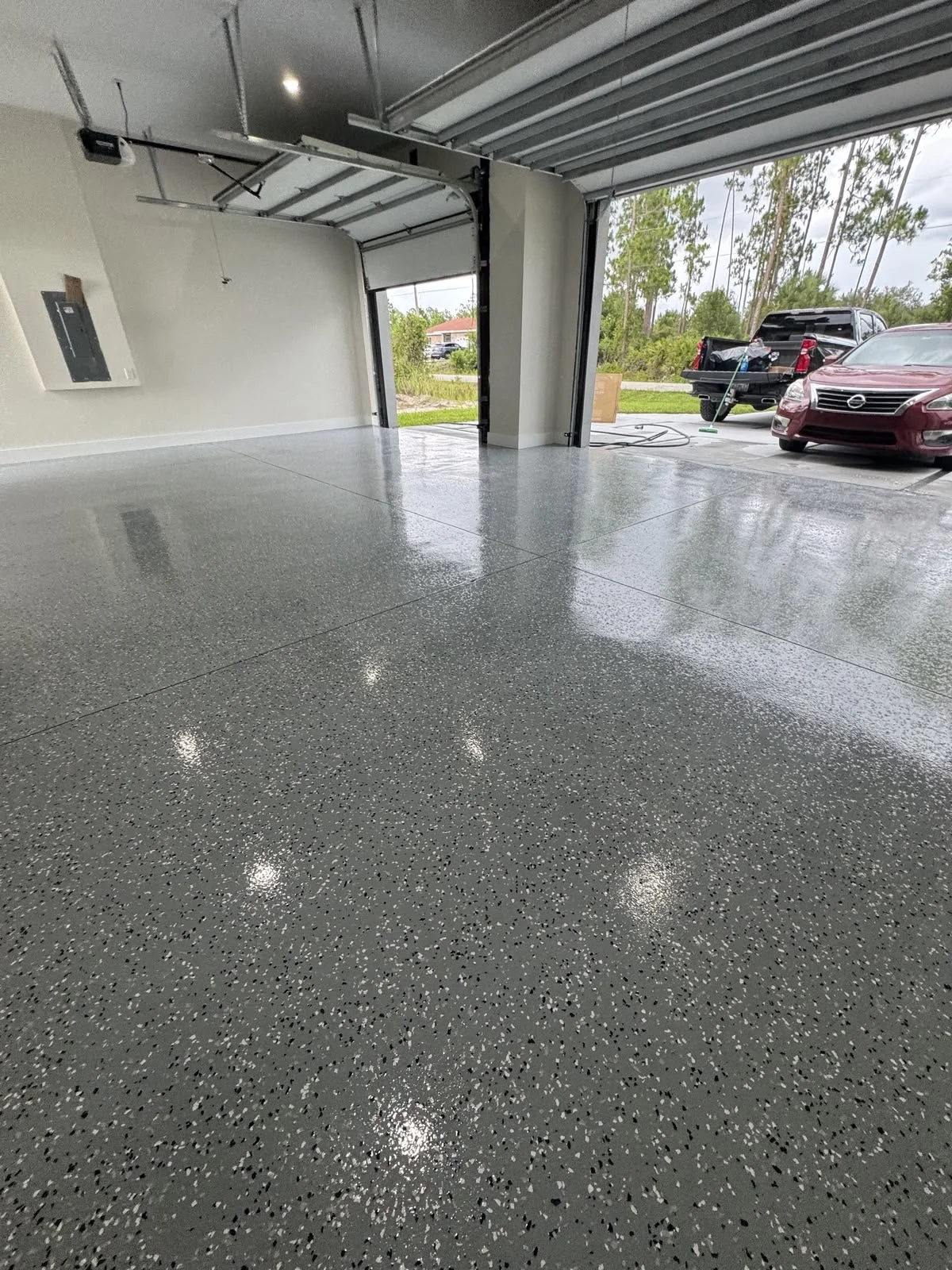 Glossy dark epoxy floor finish in a spacious garage in Orange County, CA. ZHLA Painting.