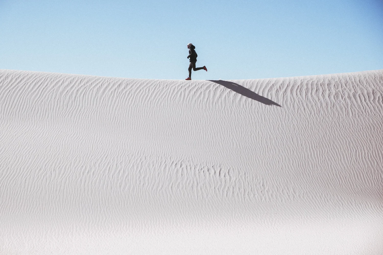 A runner crossing white dunes