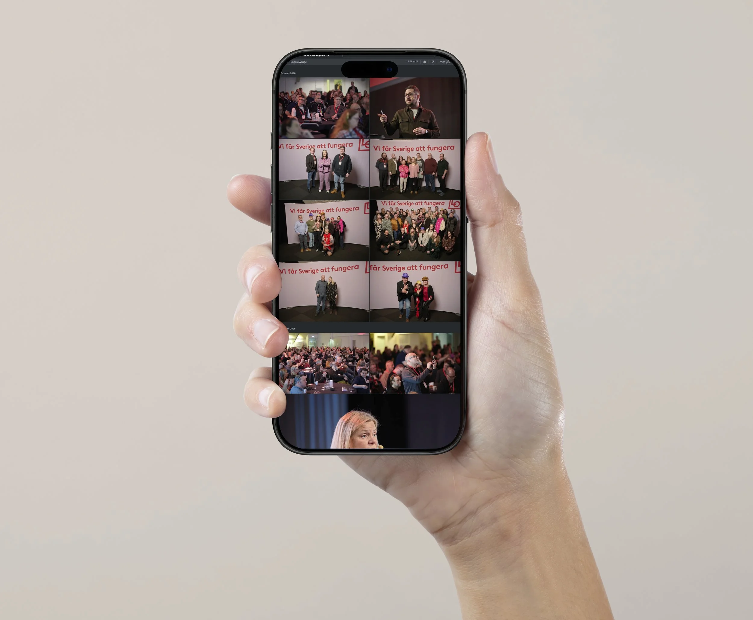 En hand håller en mobiltelefon som visar bilder från ett evenemang med människor som står framför en vägg med texten "Vi får Sverige att fungera" och personer som talar eller poserar för fotografen.