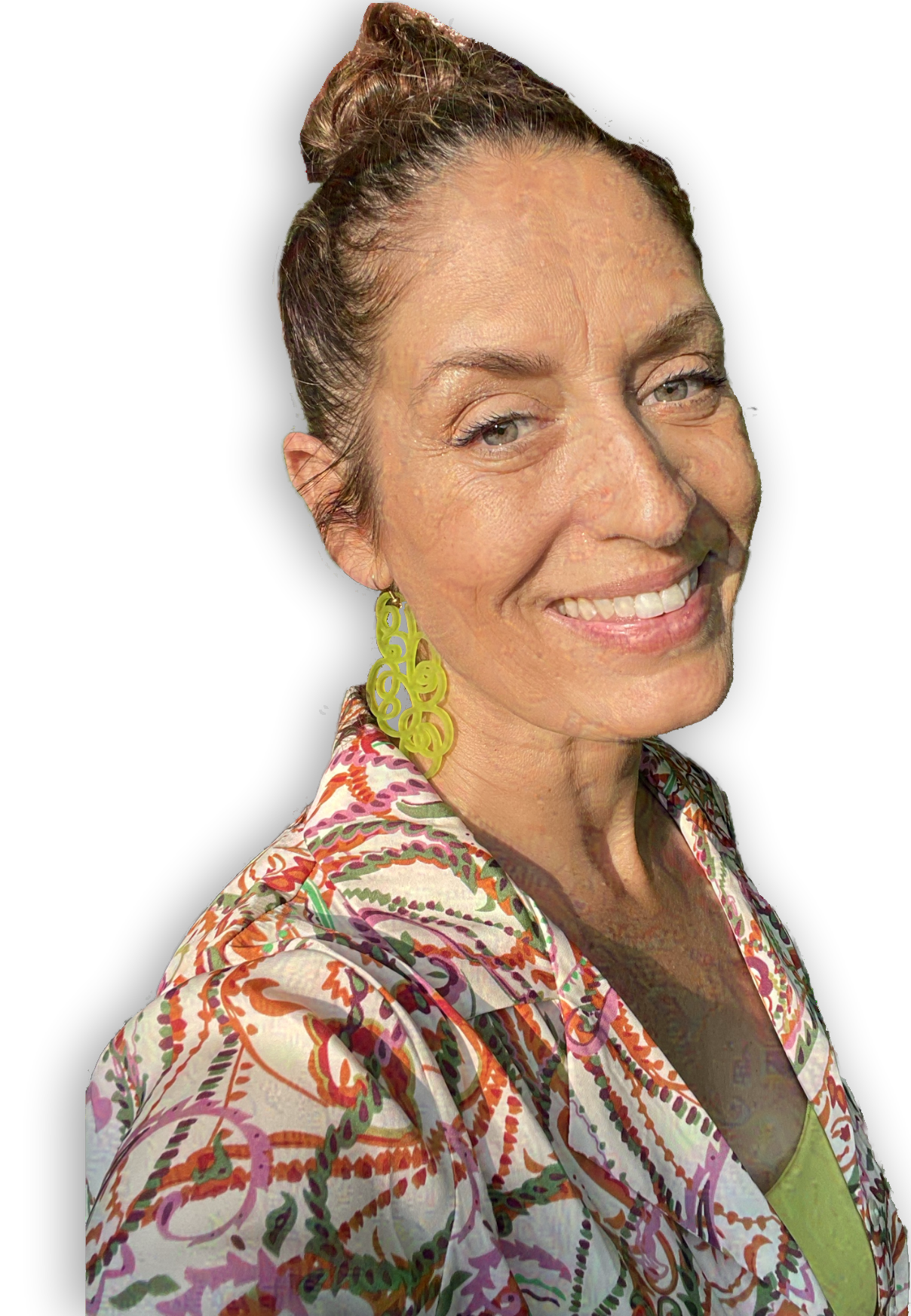 A woman with a bun hairstyle wearing yellow green earrings and a white shirt with orange, green, and pink swirls in a textured pattern..