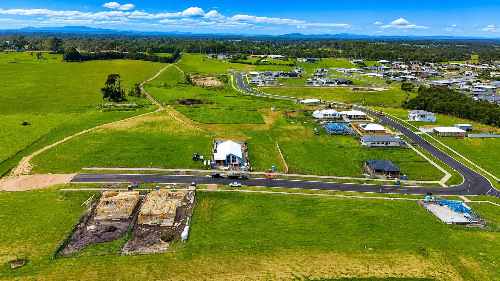 Birds eye view of coastal view estate and the building and construction works taking place. Blue skies and green grass with houses being built