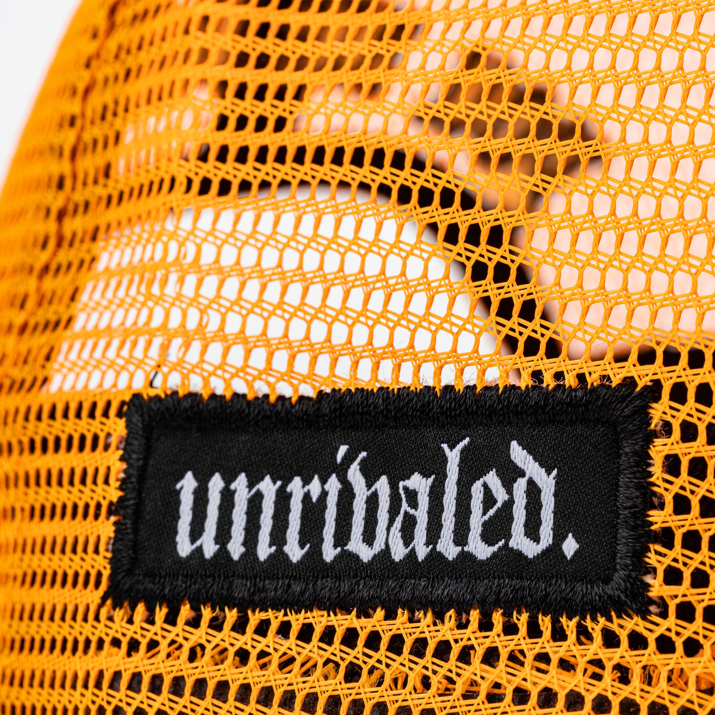 Close-up of orange mesh fabric with a black label that reads 'unbaled' in white embroidery.