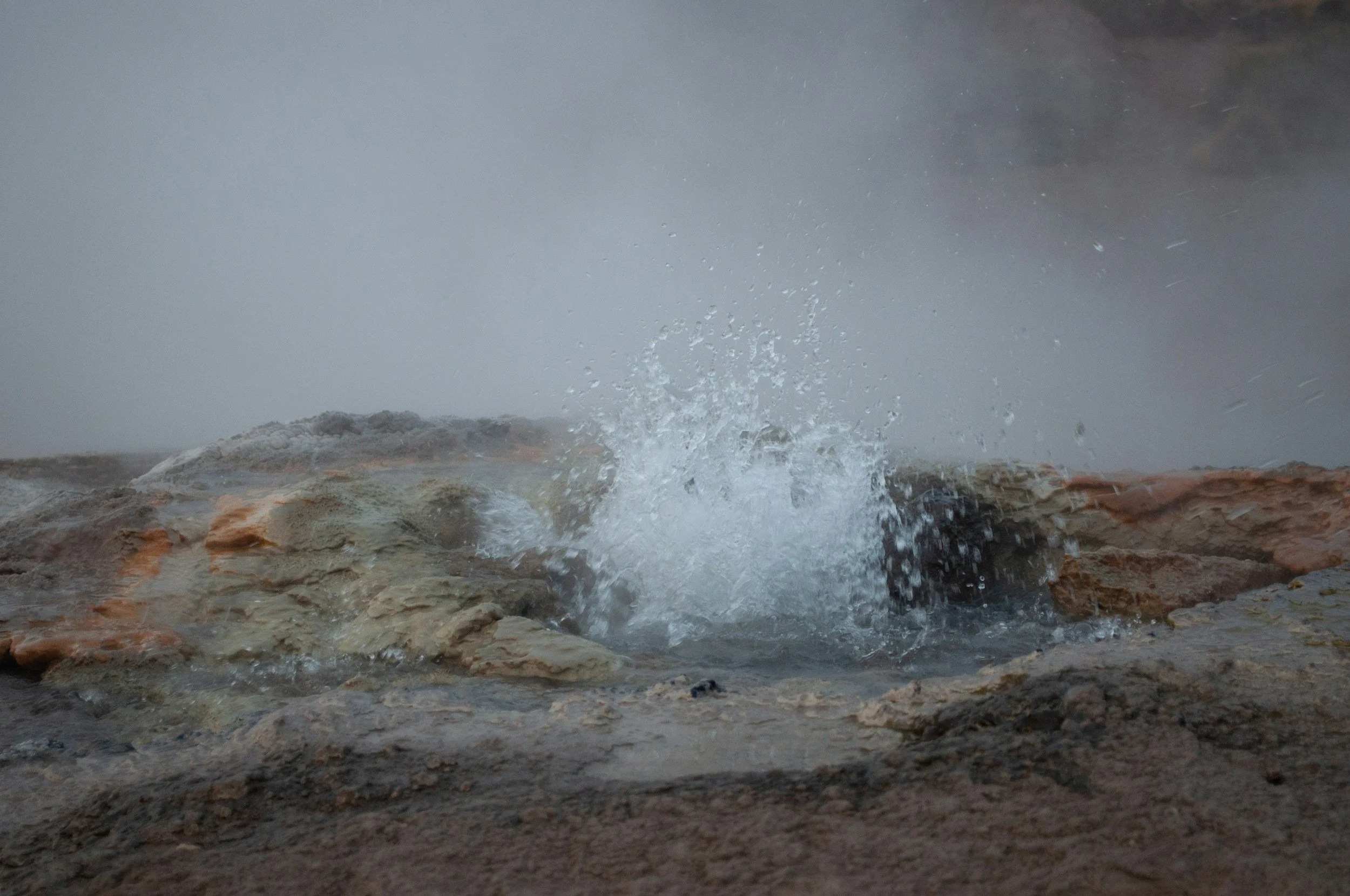 Close-up of water splashing on rocks with mist and steam in the background