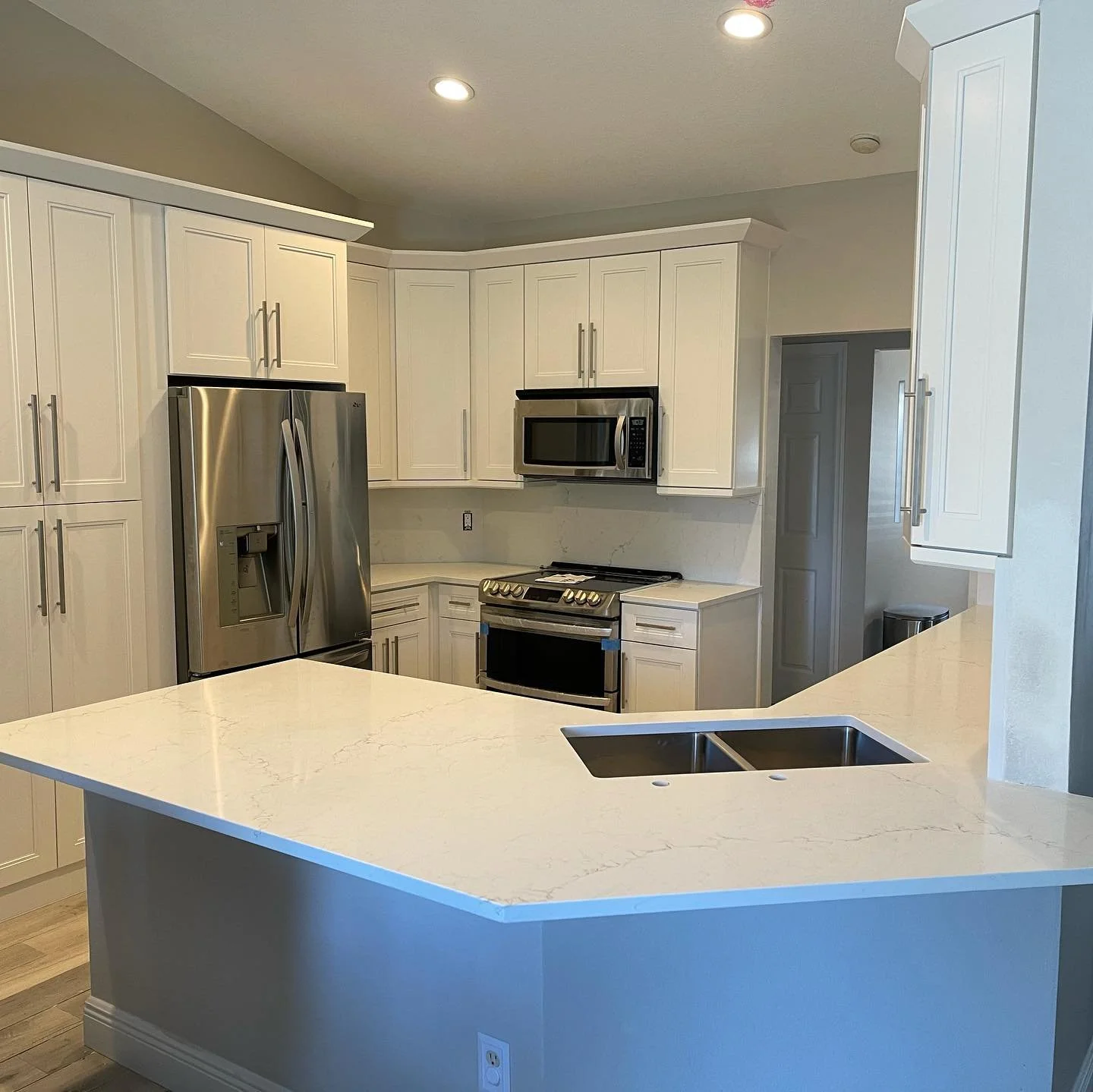 After and before pics of a kitchen with shaker white cabinets, Borghini Fantasy quartz countertop and full backsplash.