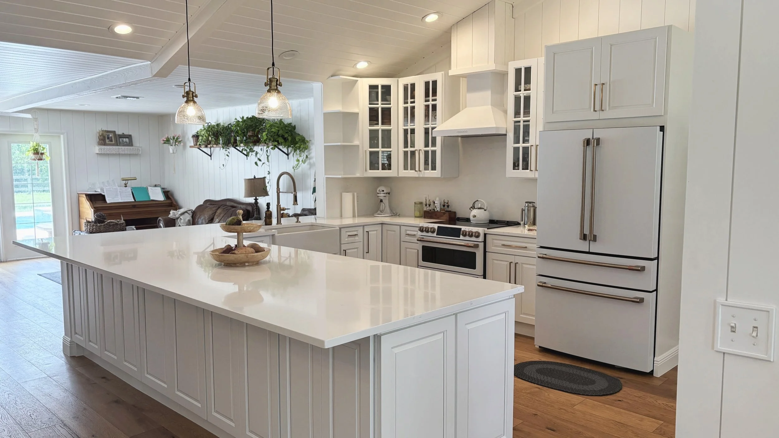 Modern white kitchen with island, stainless steel refrigerator, and pendant lighting