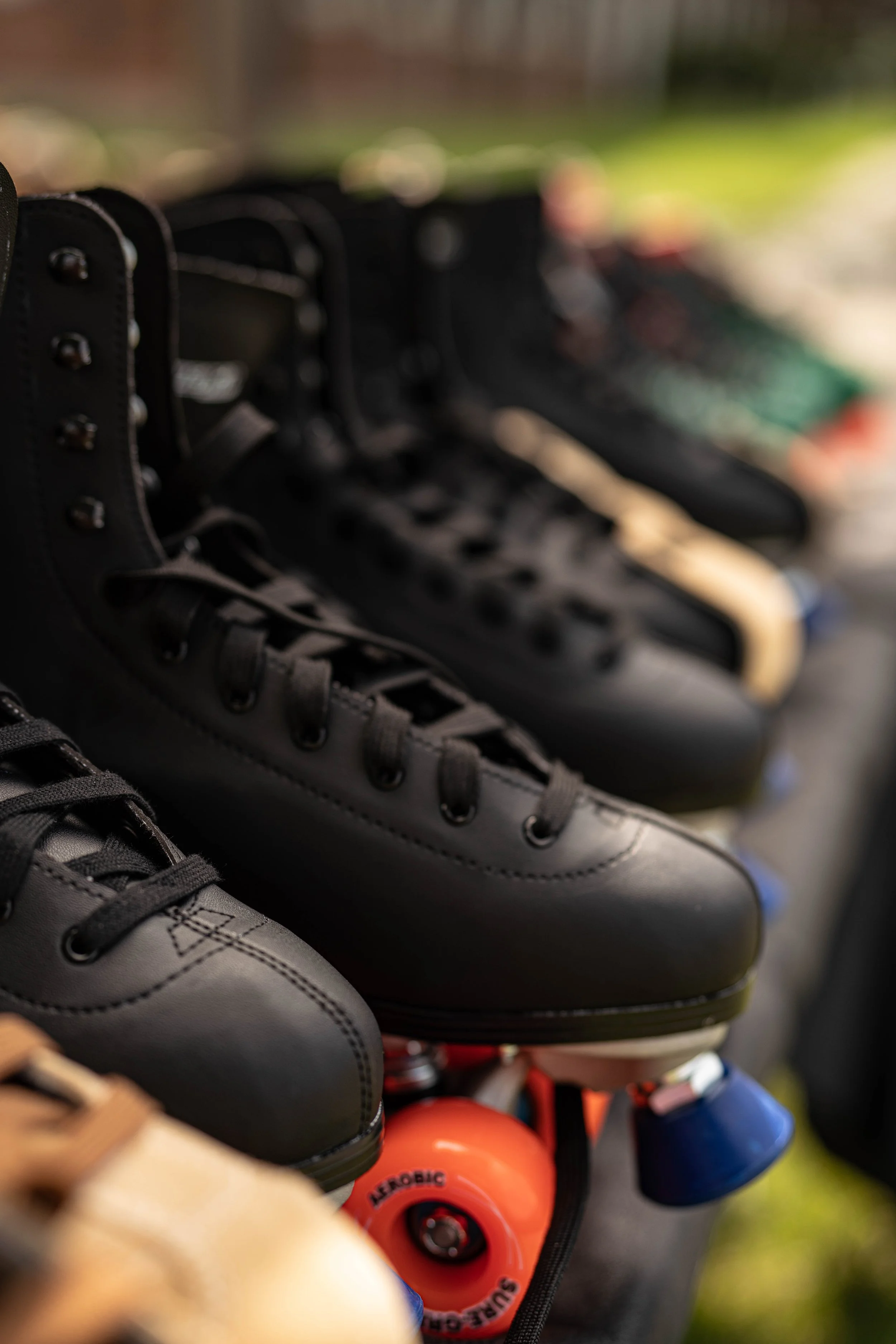 Close-up of black and white ice skates displayed together with colorful hockey pucks visible underneath.