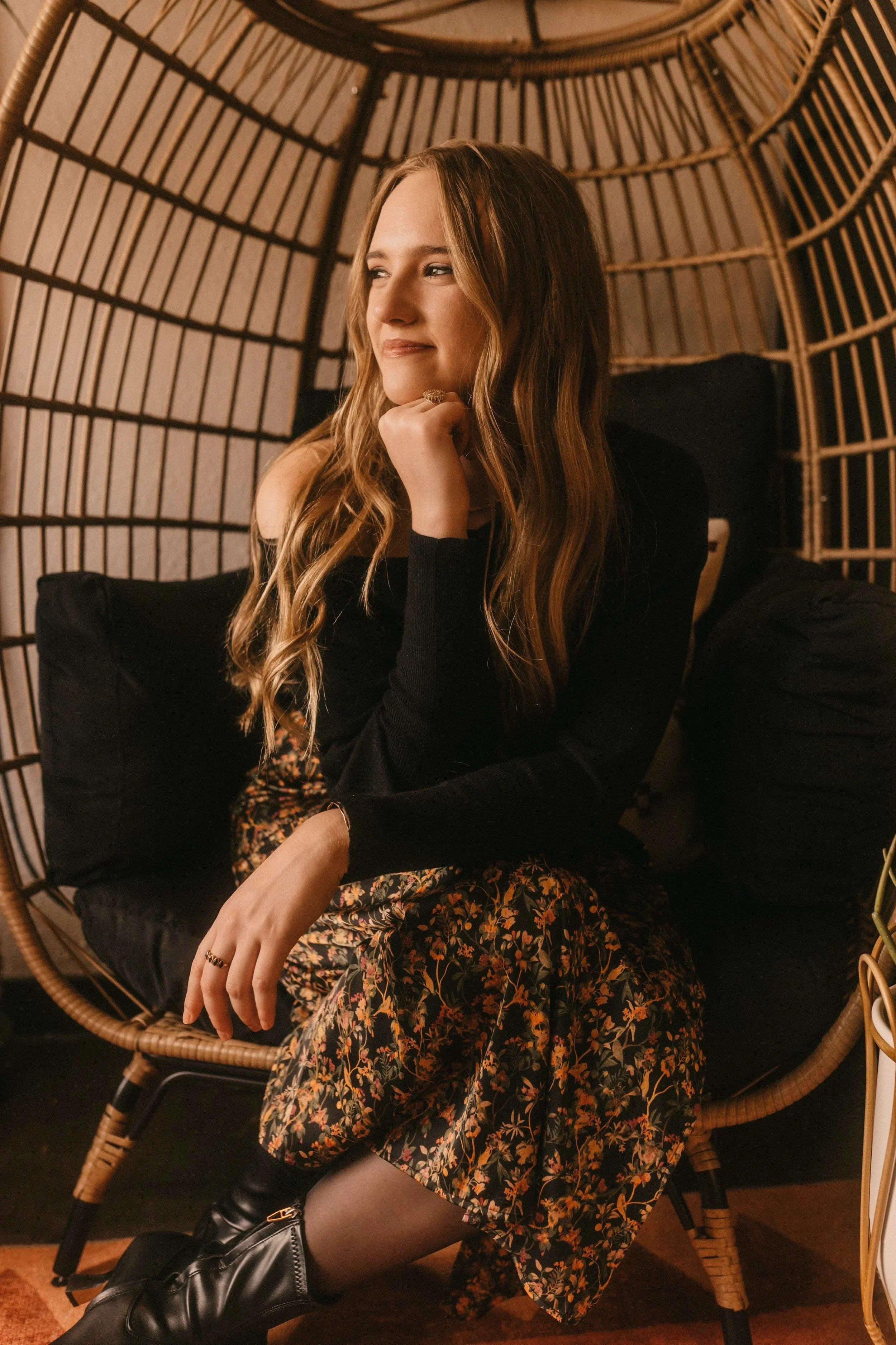 madeline stares out Casa Hogar office window posing for the camera sitting in her therapist rattan chair